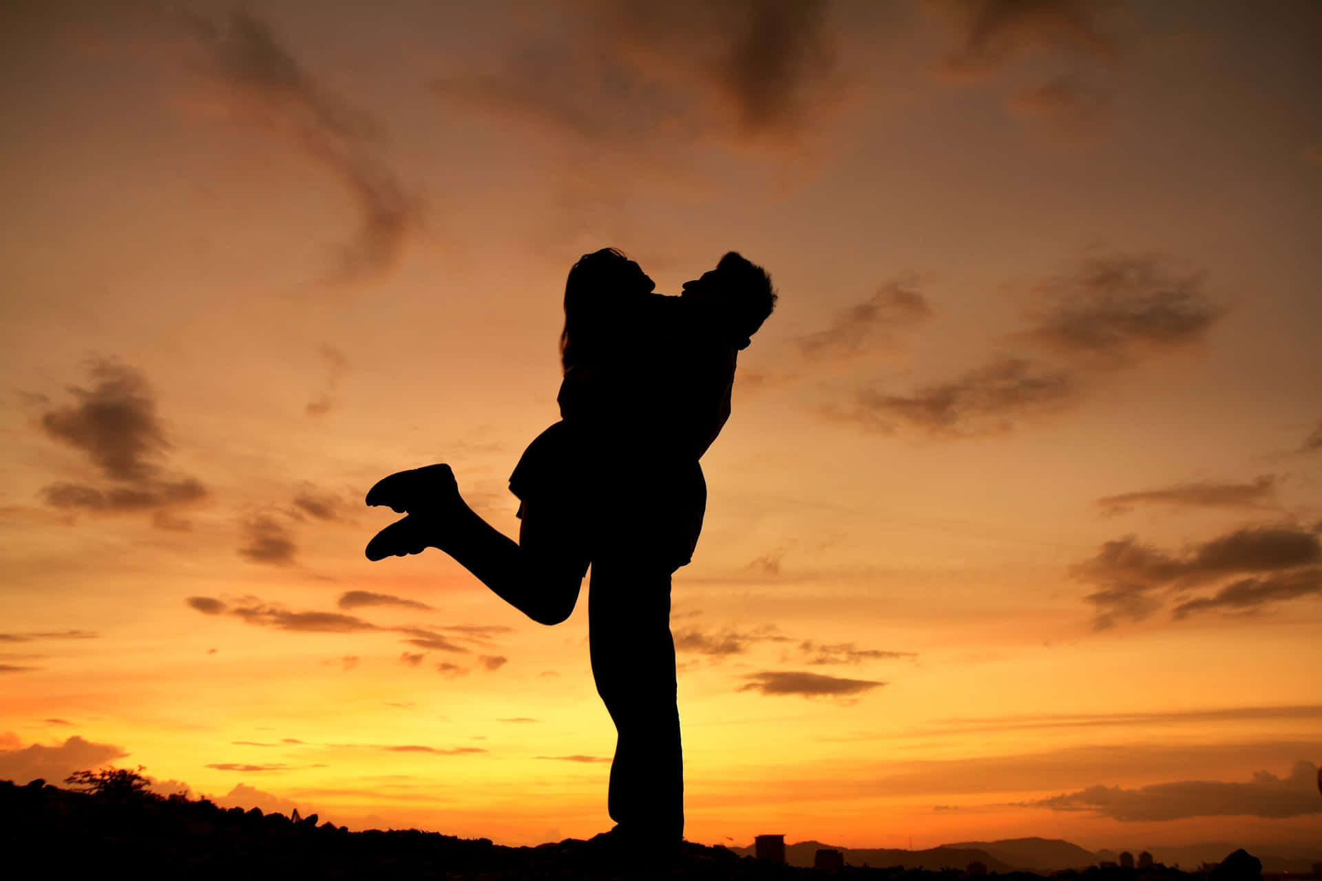 A Silhouette Of A Couple Hugging At Sunset
