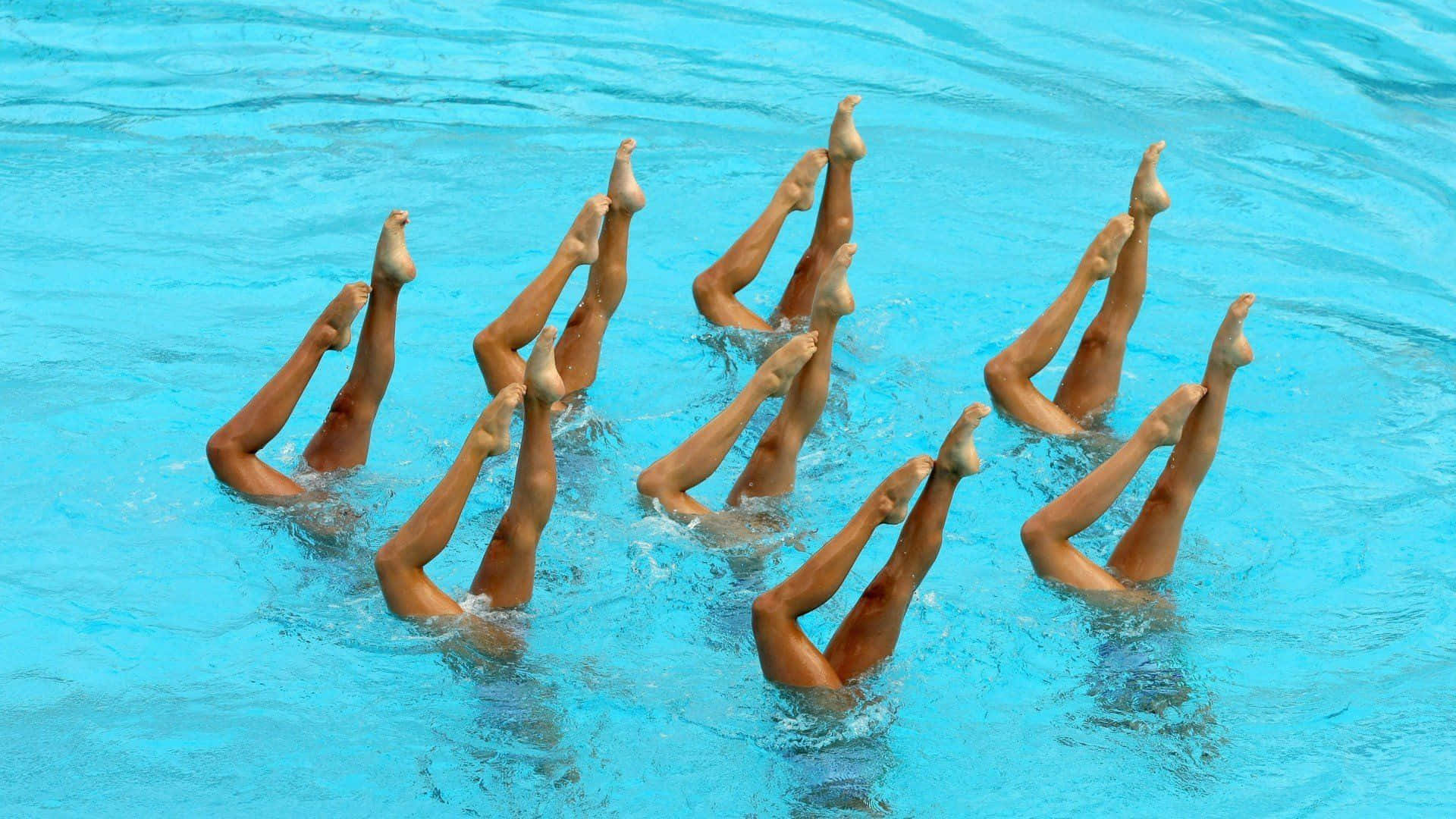A Group Of People In A Pool With Their Legs Extended