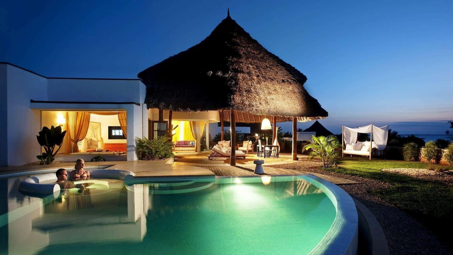 A Pool With A Thatched Roof And A Lounge Chair