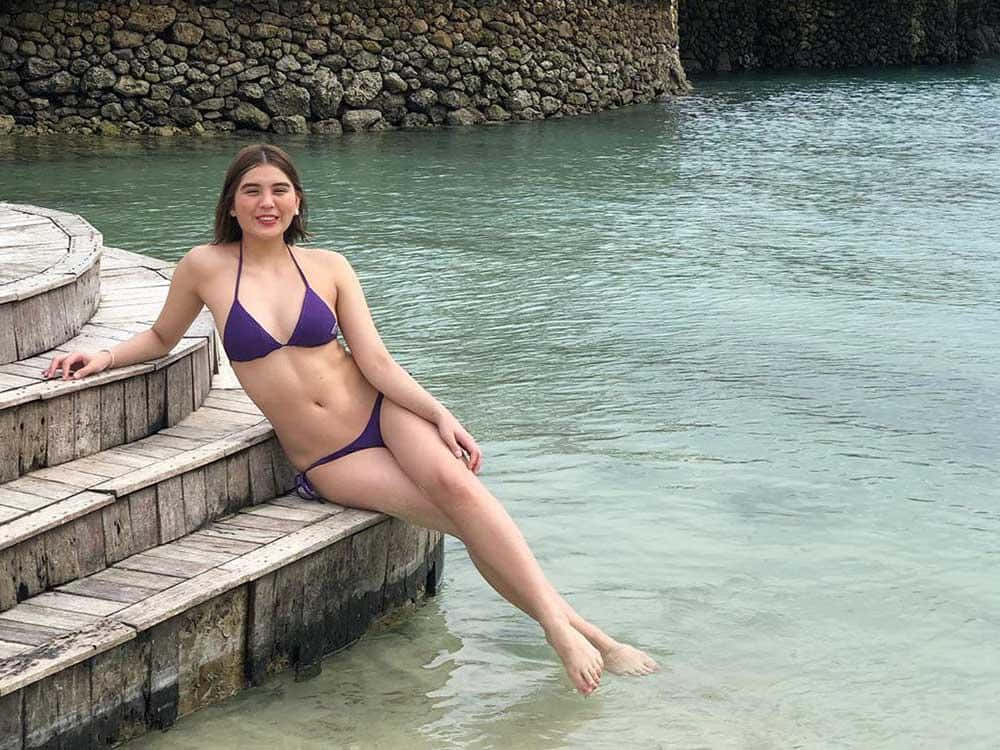A Woman In A Purple Bikini Sitting On Steps In The Water