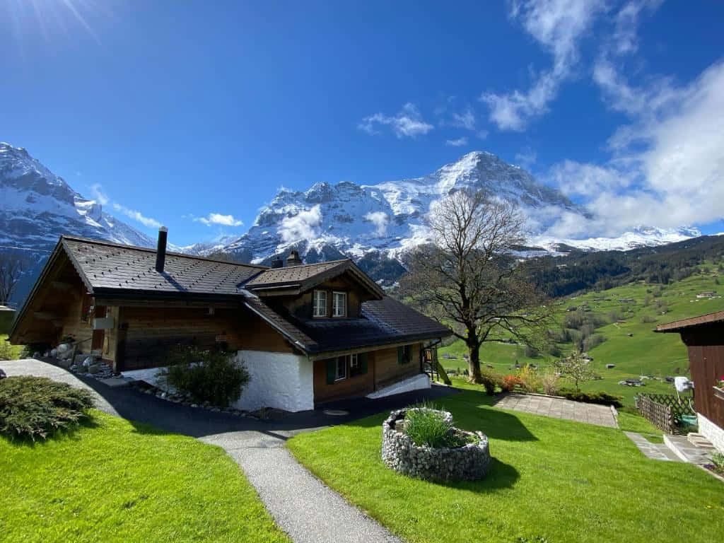 Swiss Alpine Homewith Mountain View Wallpaper
