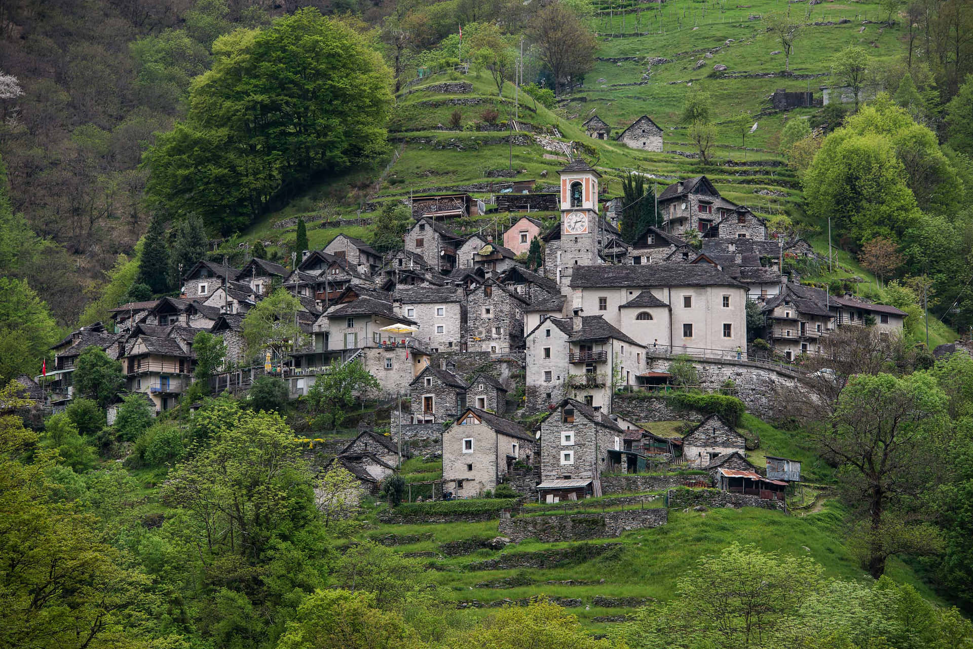 A Village On A Hillside With Trees And Greenery