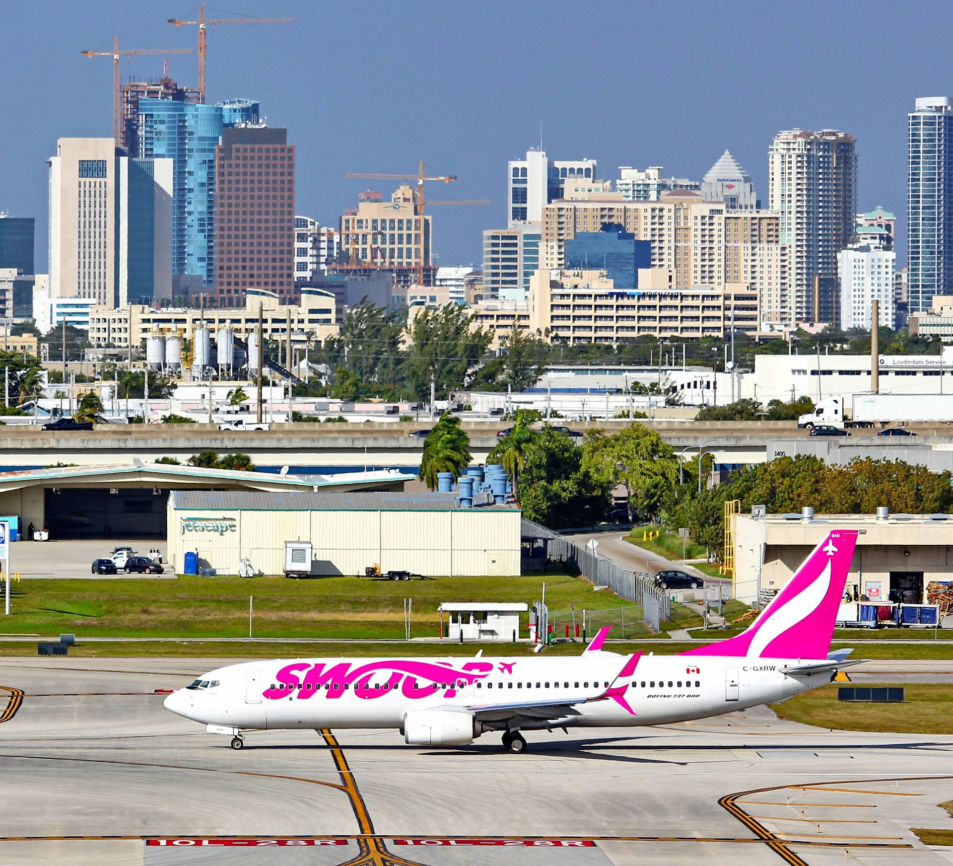 Aviónde Swoop Airlines Con Vista A La Ciudad. Fondo de pantalla