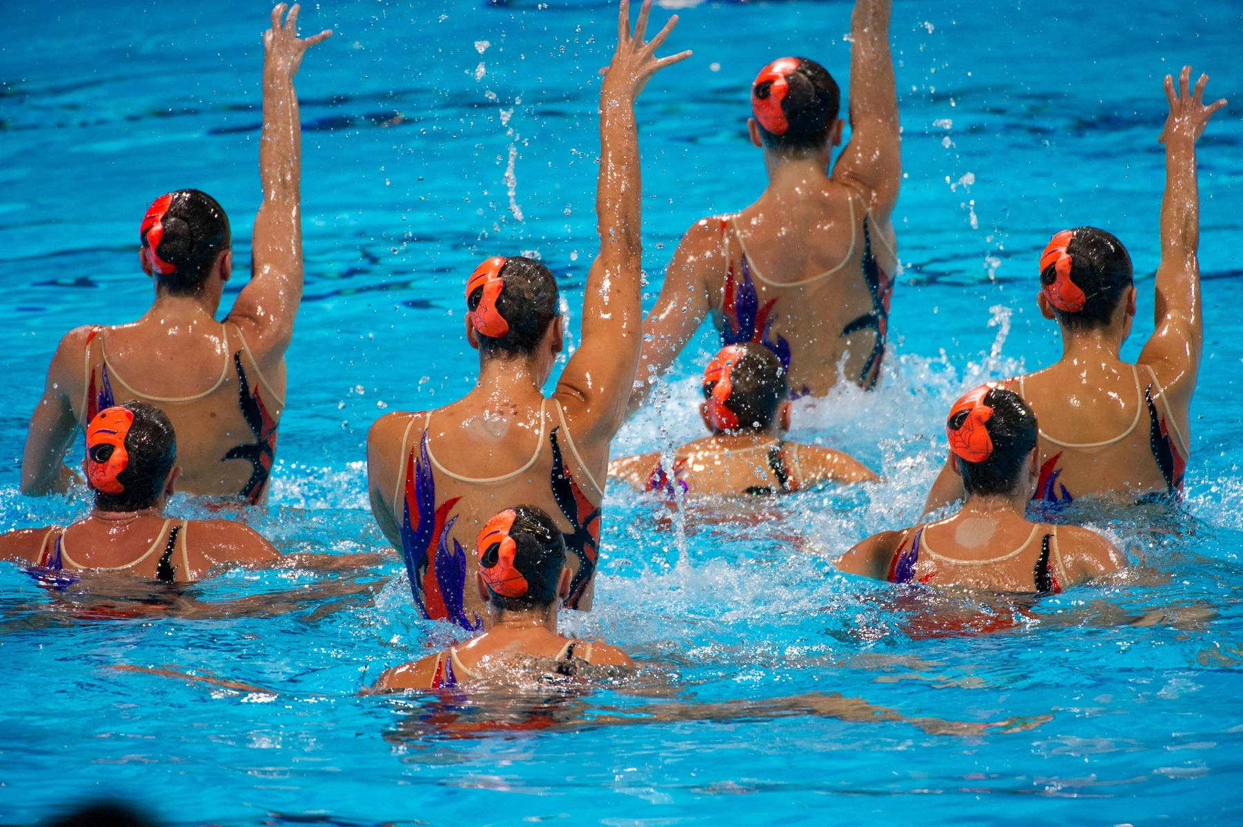 Synchronized Swimmers With Hands Up in Perfect Harmony Wallpaper