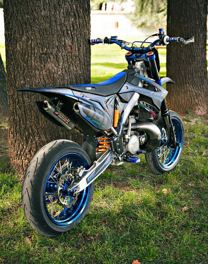 T M Racing Supermoto Geparkeerd Tussen Bomen Achtergrond