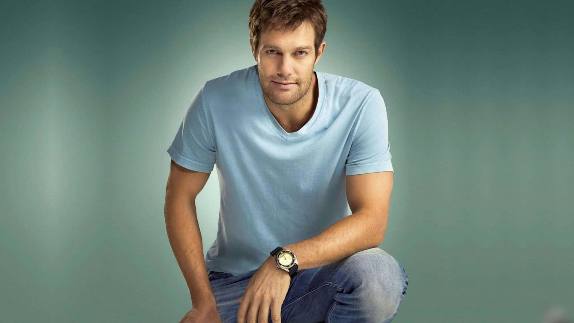 A Man In A Blue Shirt And Jeans Posing