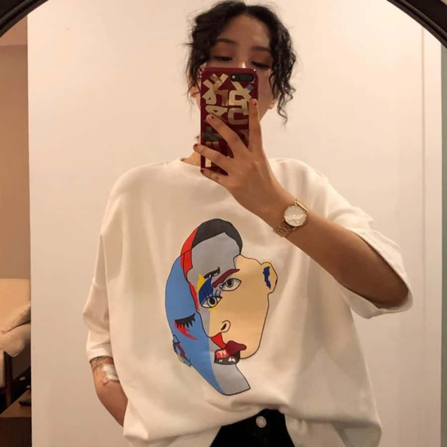 A Woman Taking A Selfie In A Mirror Wearing A T - Shirt With A Cartoon Face On It