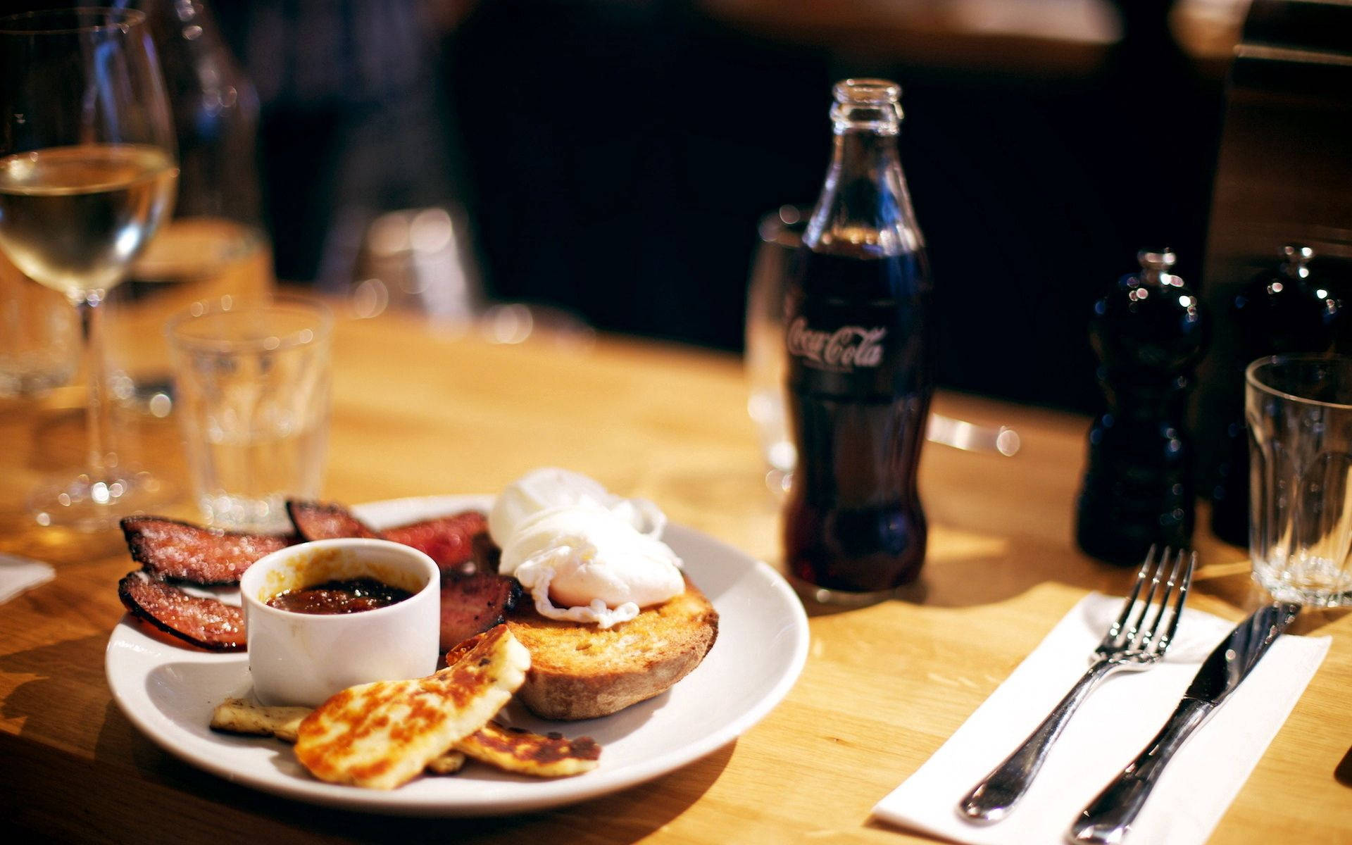 Food And Drink Table Wallpaper — A warm wooden table set with a plate of eggs benedict bacon hash browns and a glass of white wine.