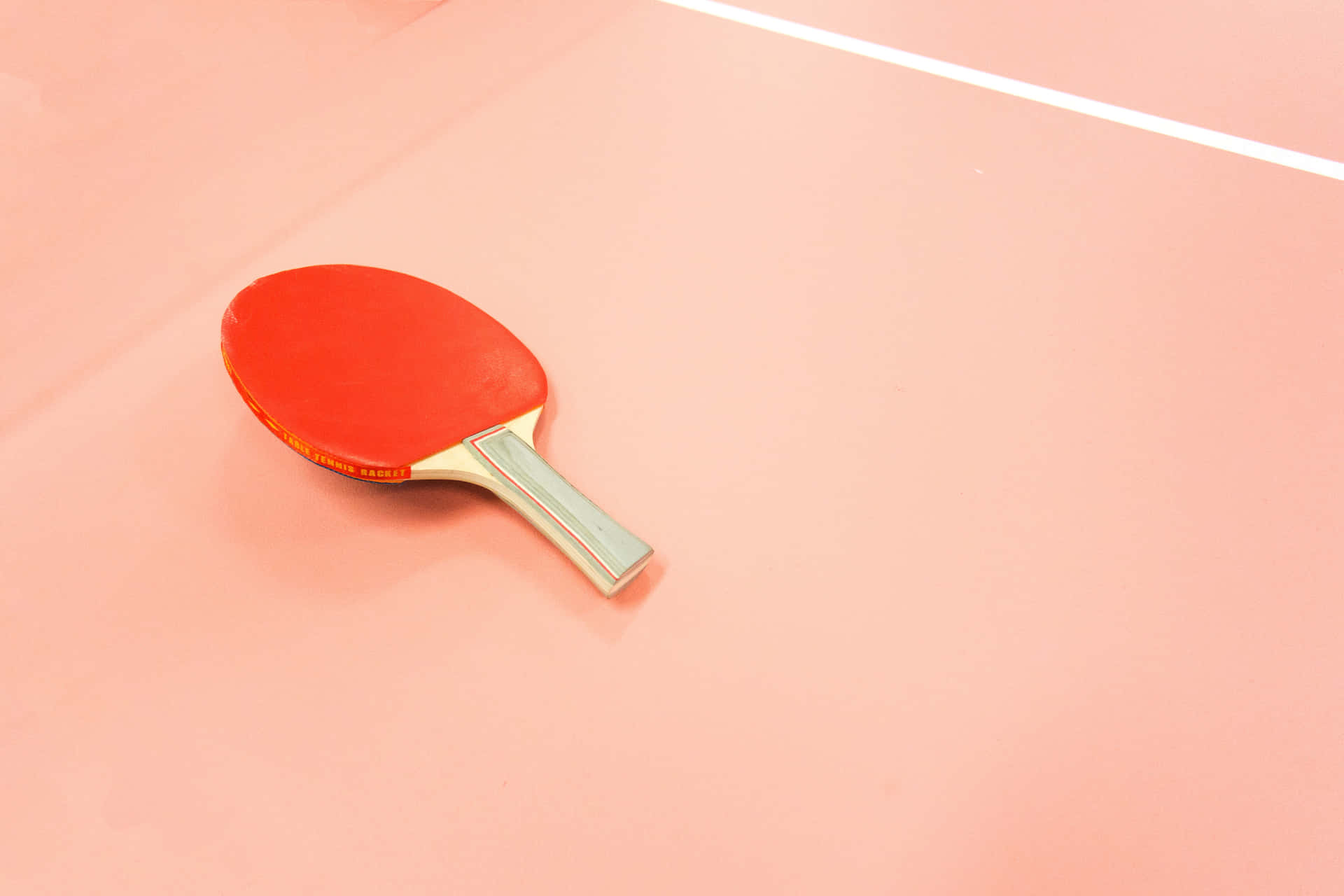 Unapaleta De Ping Pong Roja En Una Mesa Rosa