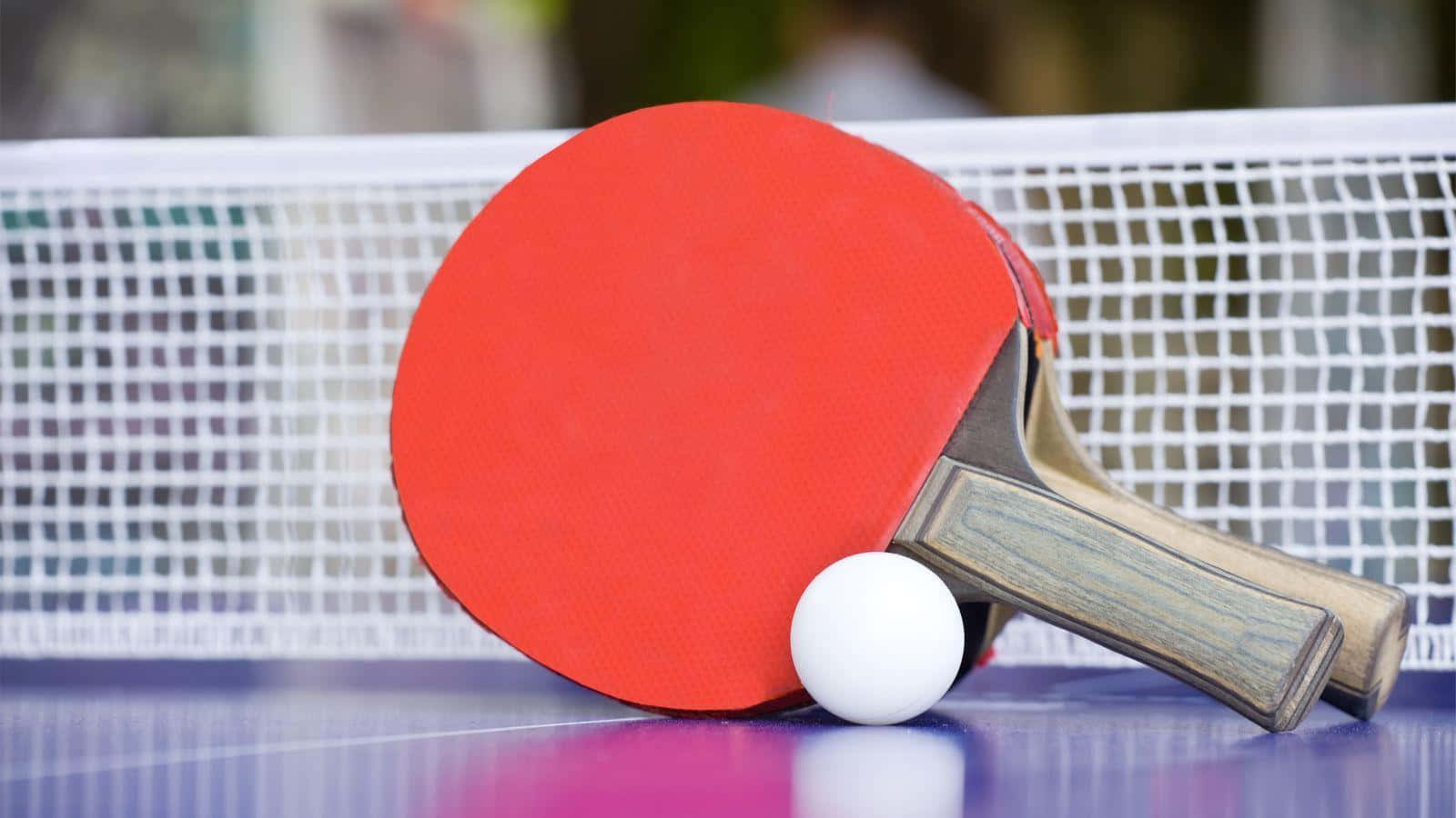 A Ping Pong Paddle And Ball On A Table