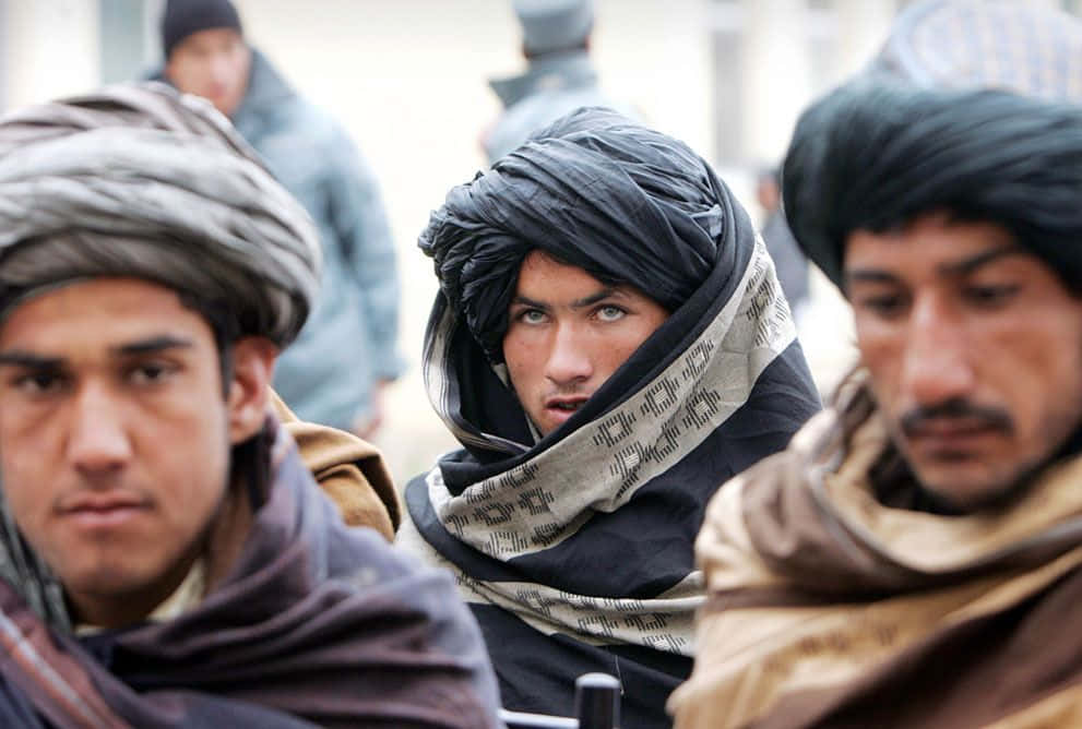 Taliban fighters wearing camouflage and carrying weaponry amidst rugged terrain.