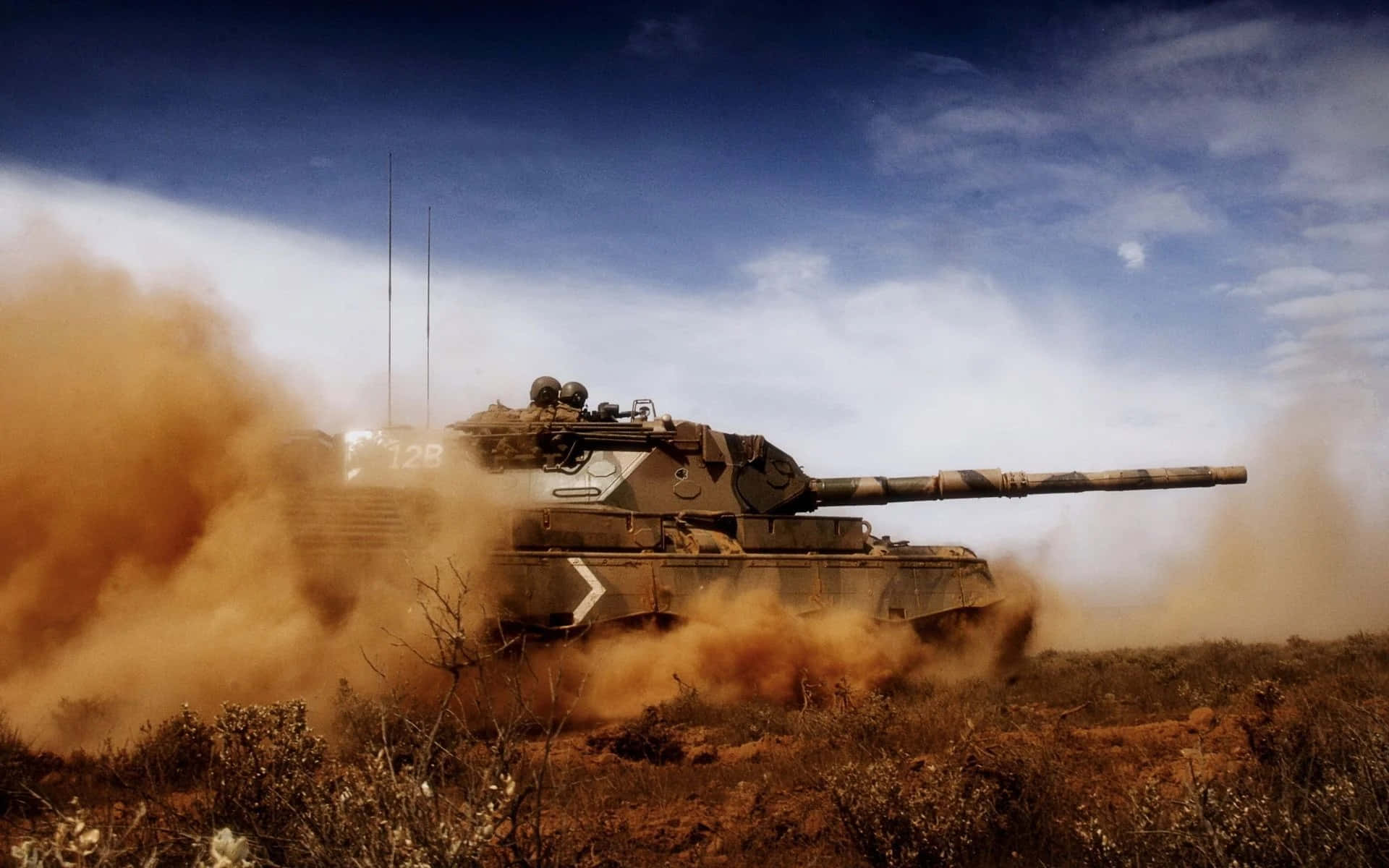 A Tank Is Driving Through A Field With Dust