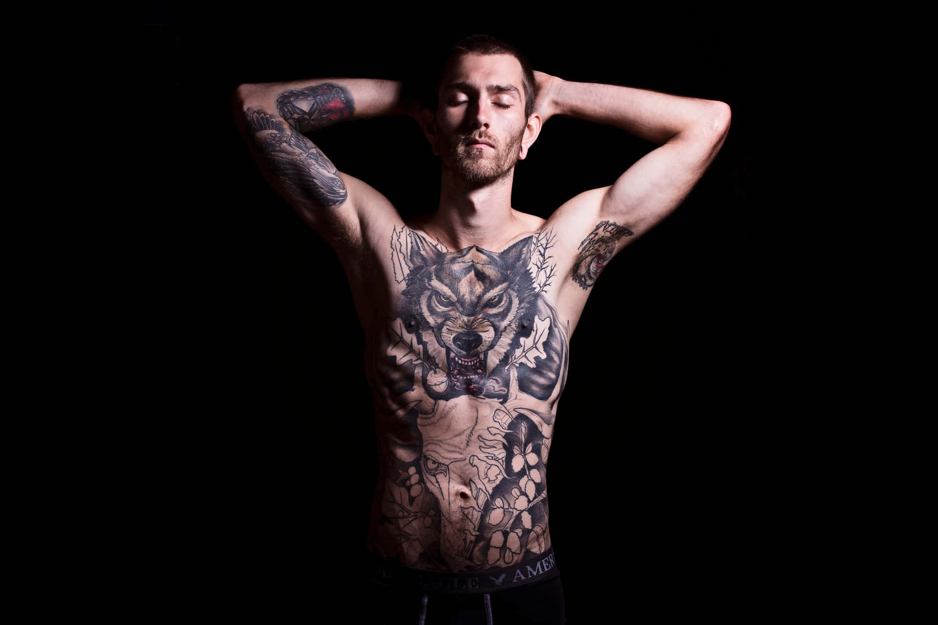 A Man With Tattoos Posing On A Black Background