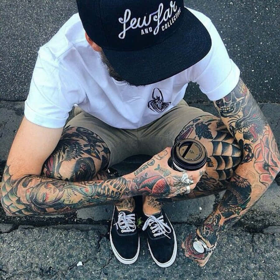 A Man With Tattoos Sitting On The Ground
