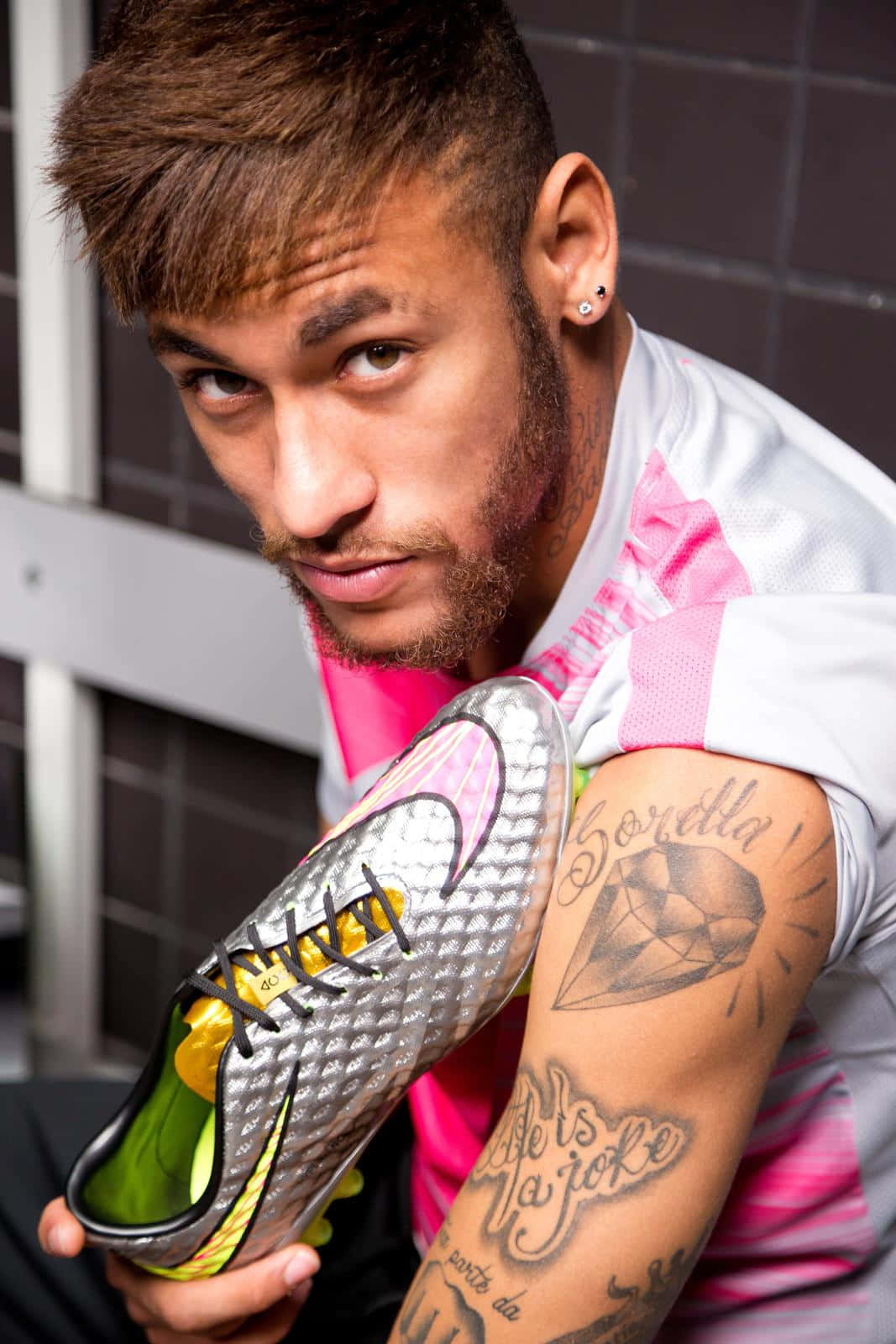 A Man With Tattoos Holding A Soccer Shoe