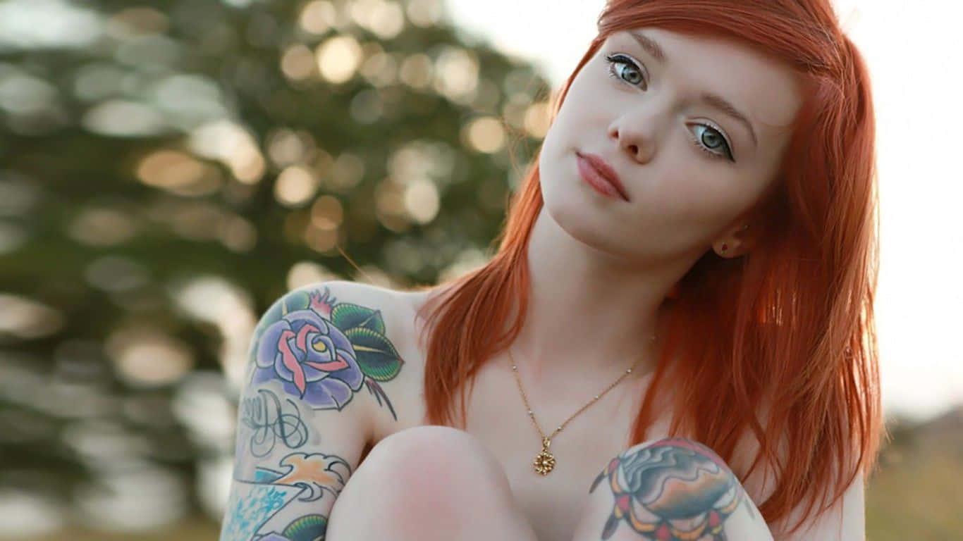 A Girl With Red Hair And Tattoos Sitting On The Ground