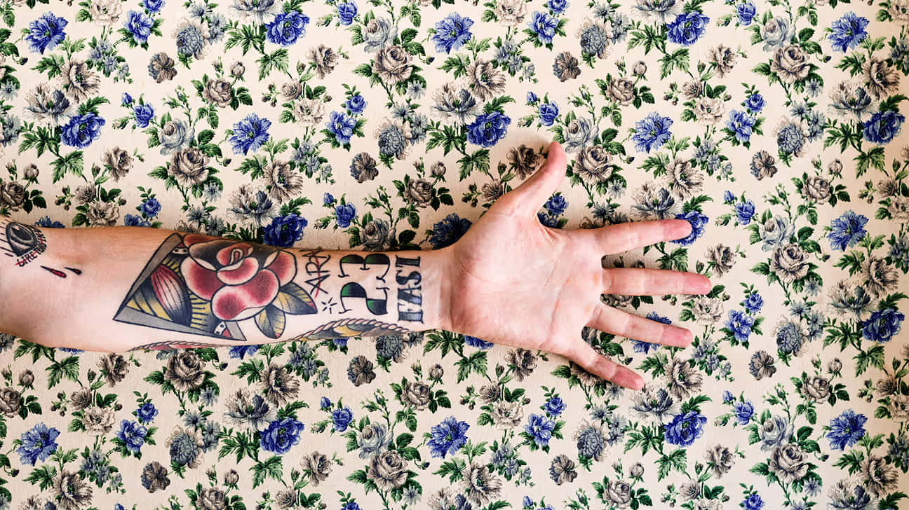 Tattooed Wrist Against Floral Backdrop Wallpaper