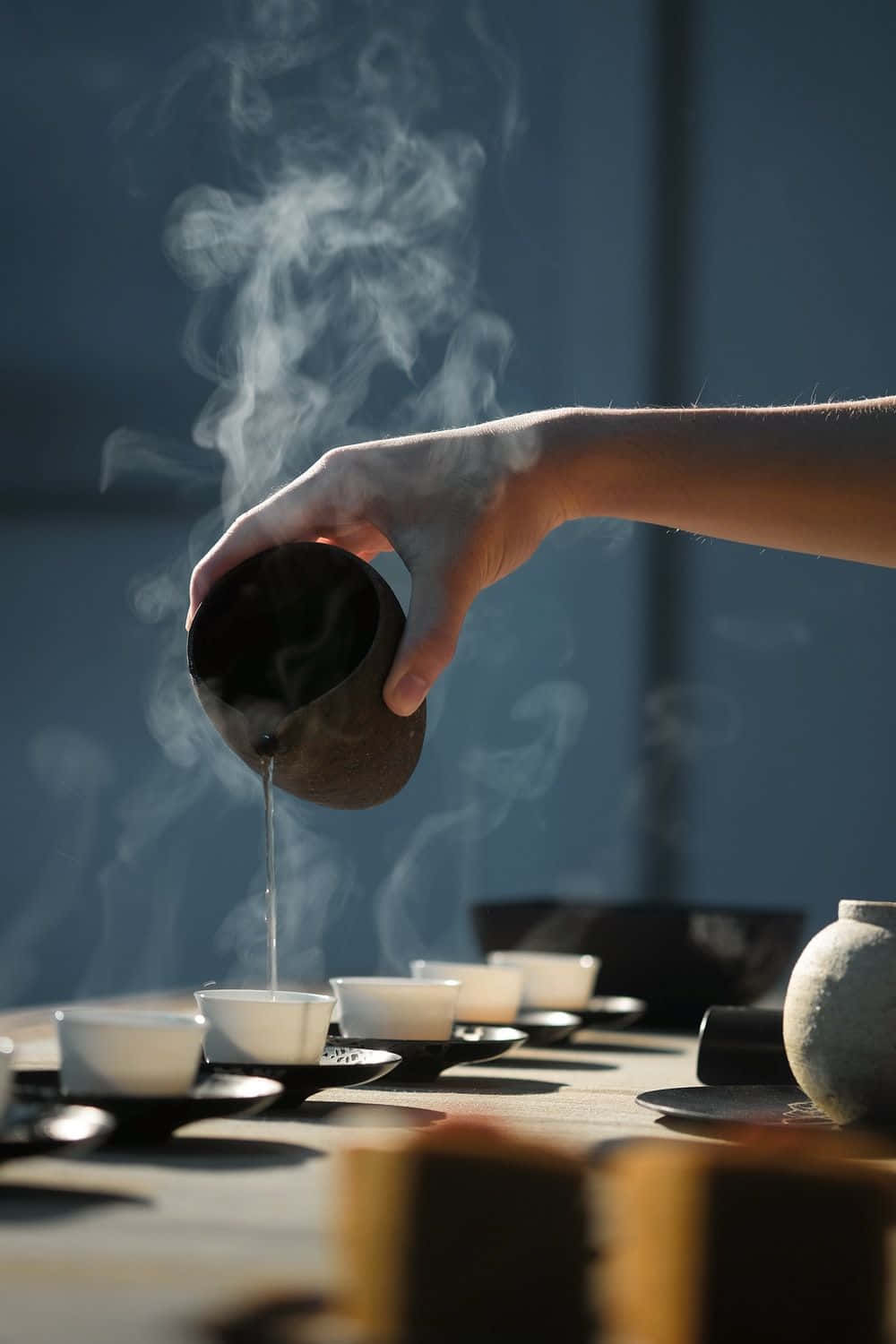 A Person Pouring Tea Into Cups On A Table