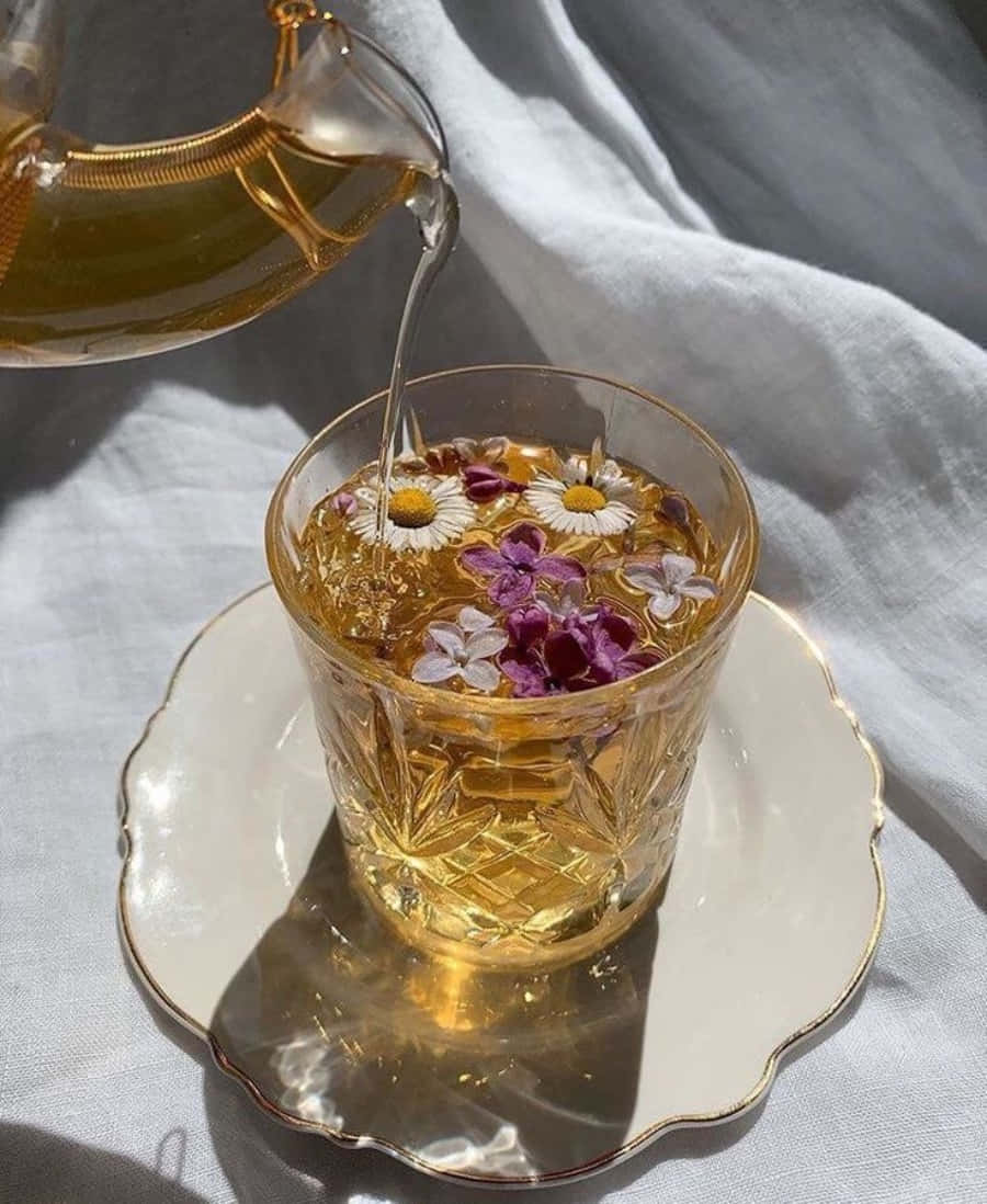 A Cup Of Tea With Flowers Being Poured Into It