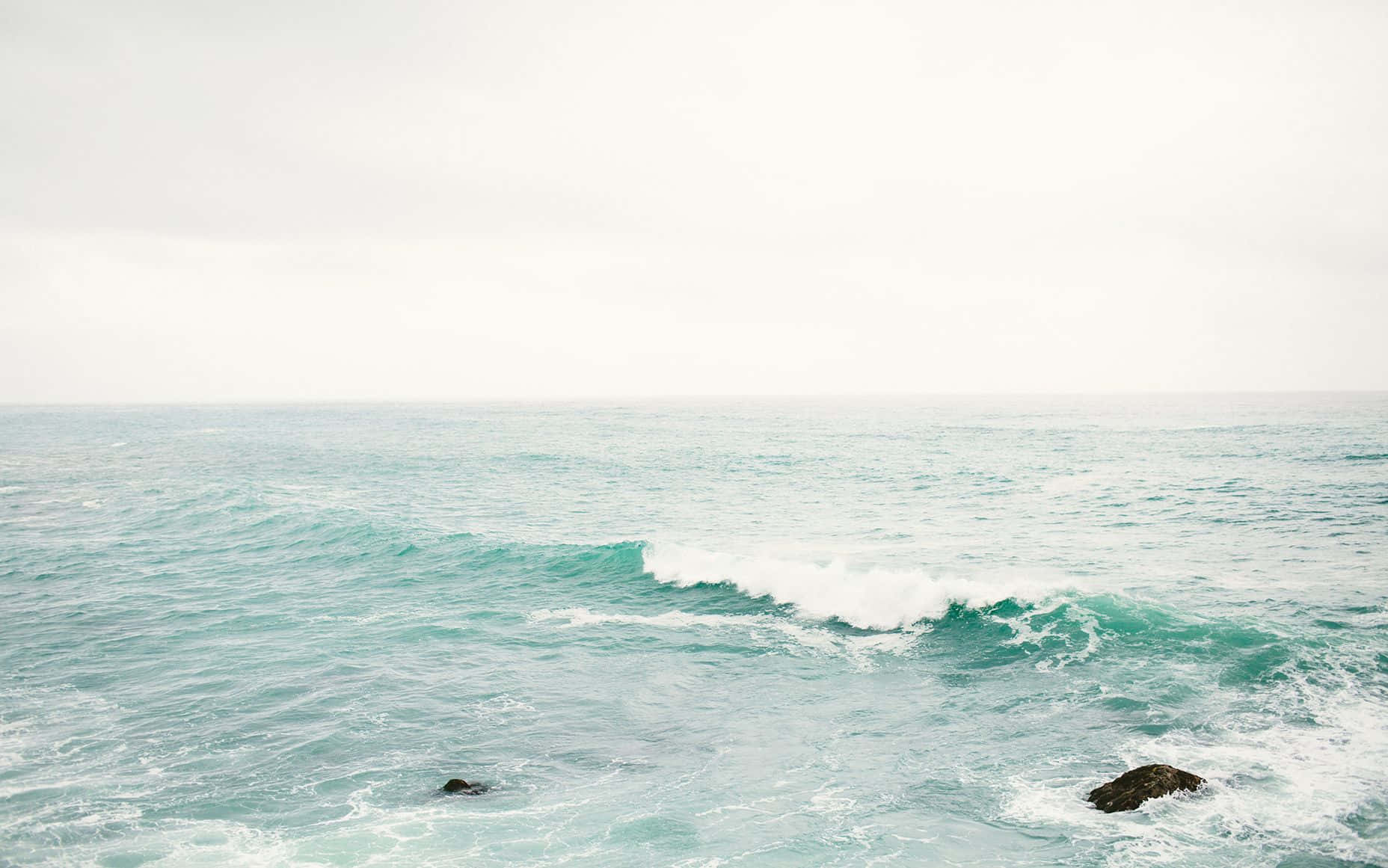 En mand står på en klippe i havet. Wallpaper