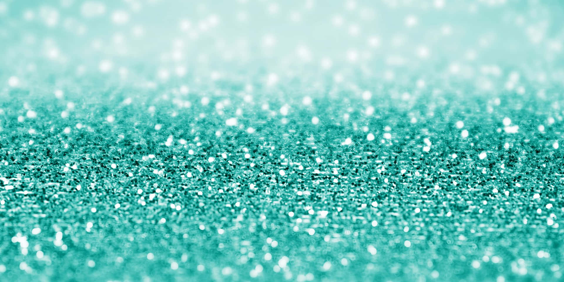 Sparkling teal glitter on an abstract blue and green background.