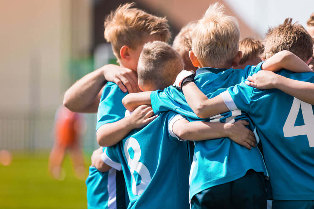 A Group Of Boys Huddle Together On A Soccer Field