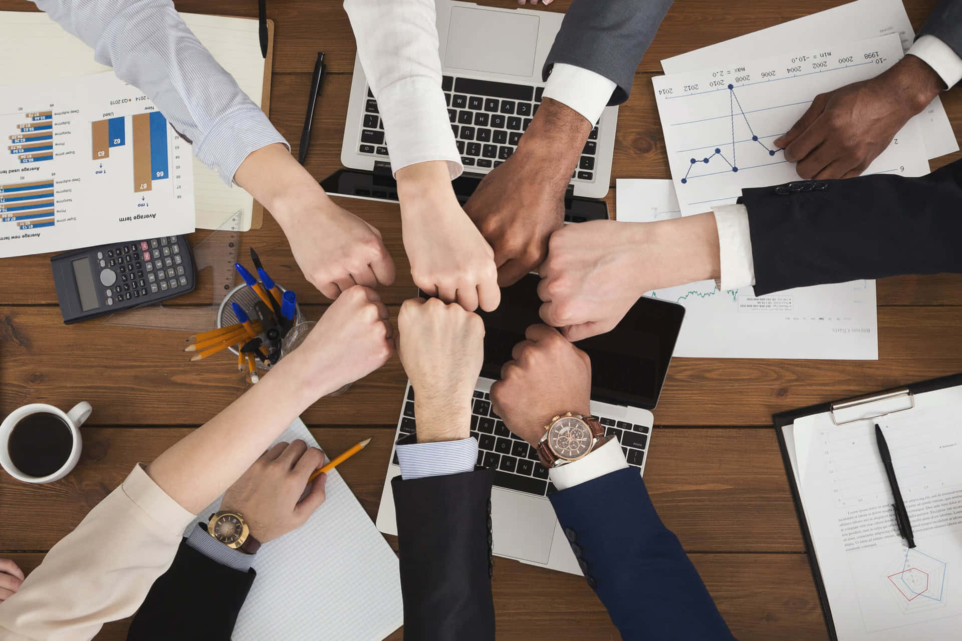 Business People Putting Their Hands Together On A Table Wallpaper