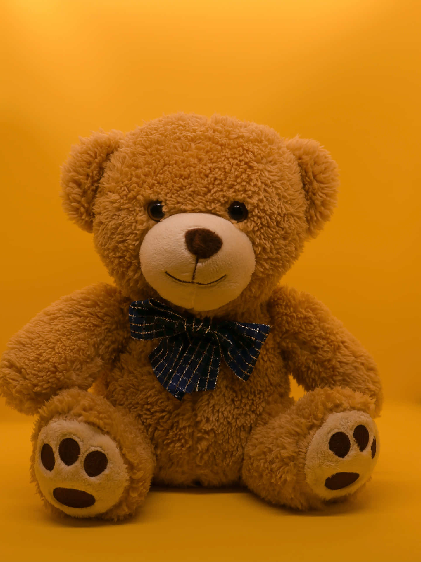 A Teddy Bear Sitting On A Yellow Background