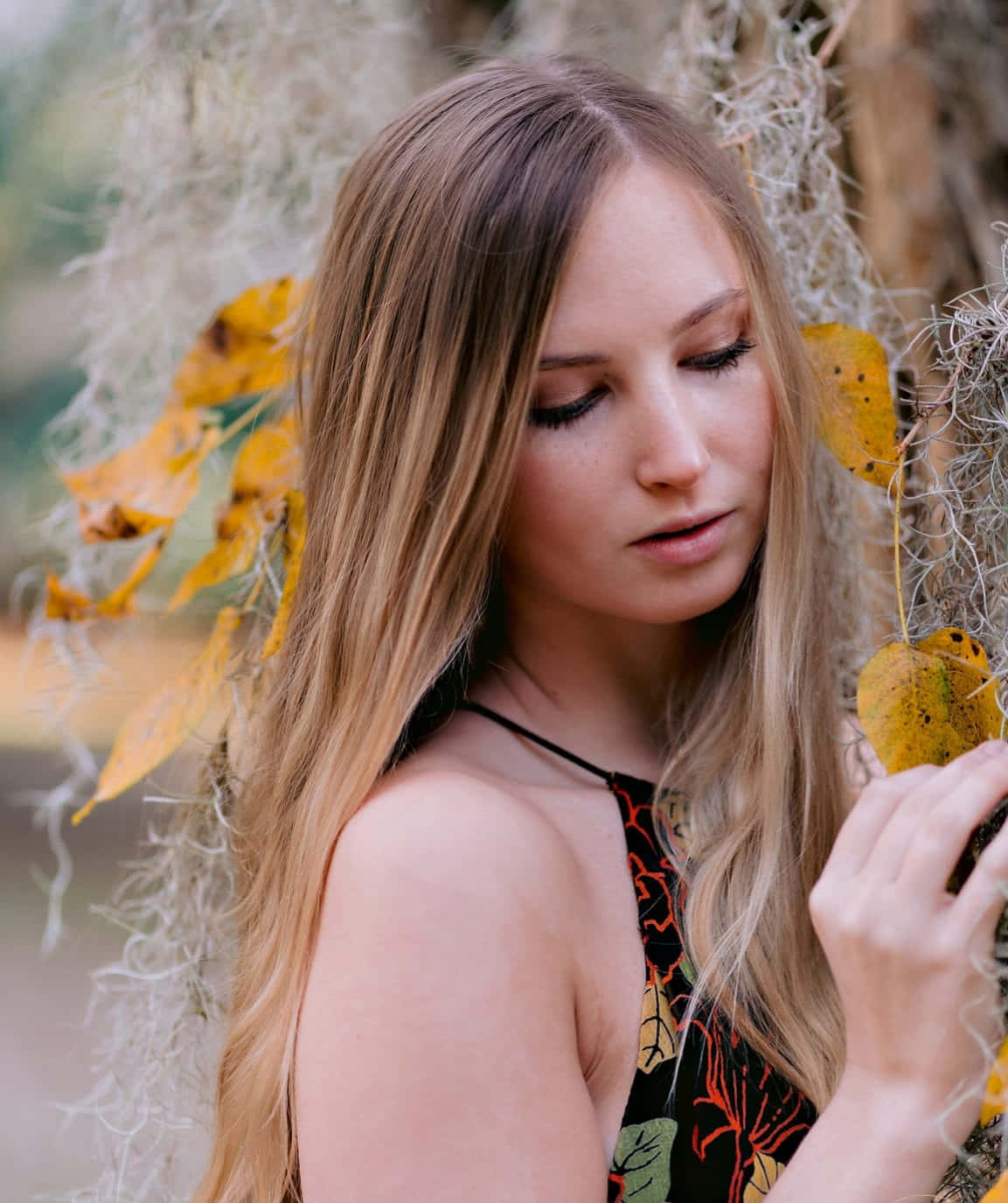 a young woman leaning against a tree with moss