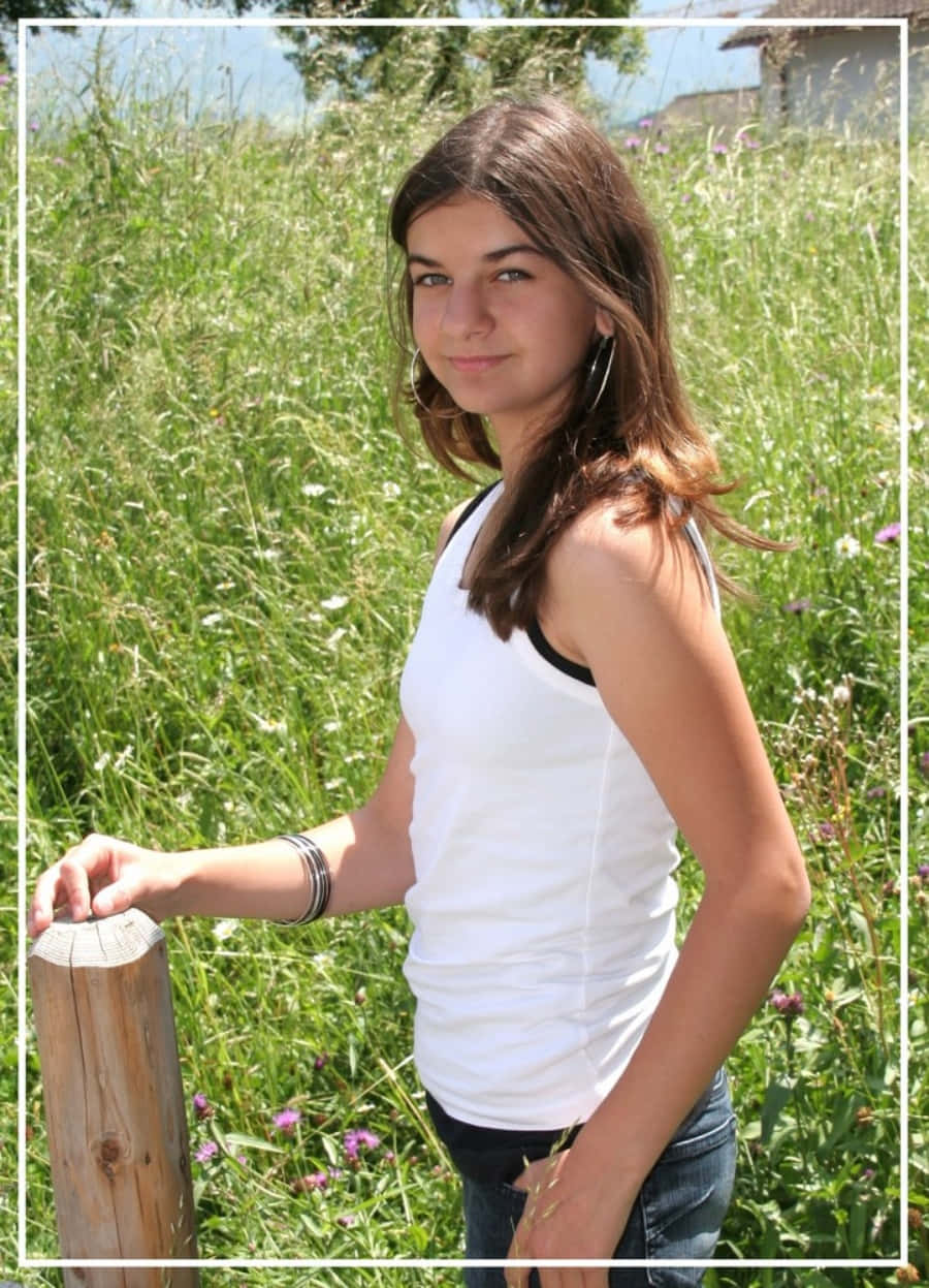 A Girl In A White Tank Top Standing In A Field