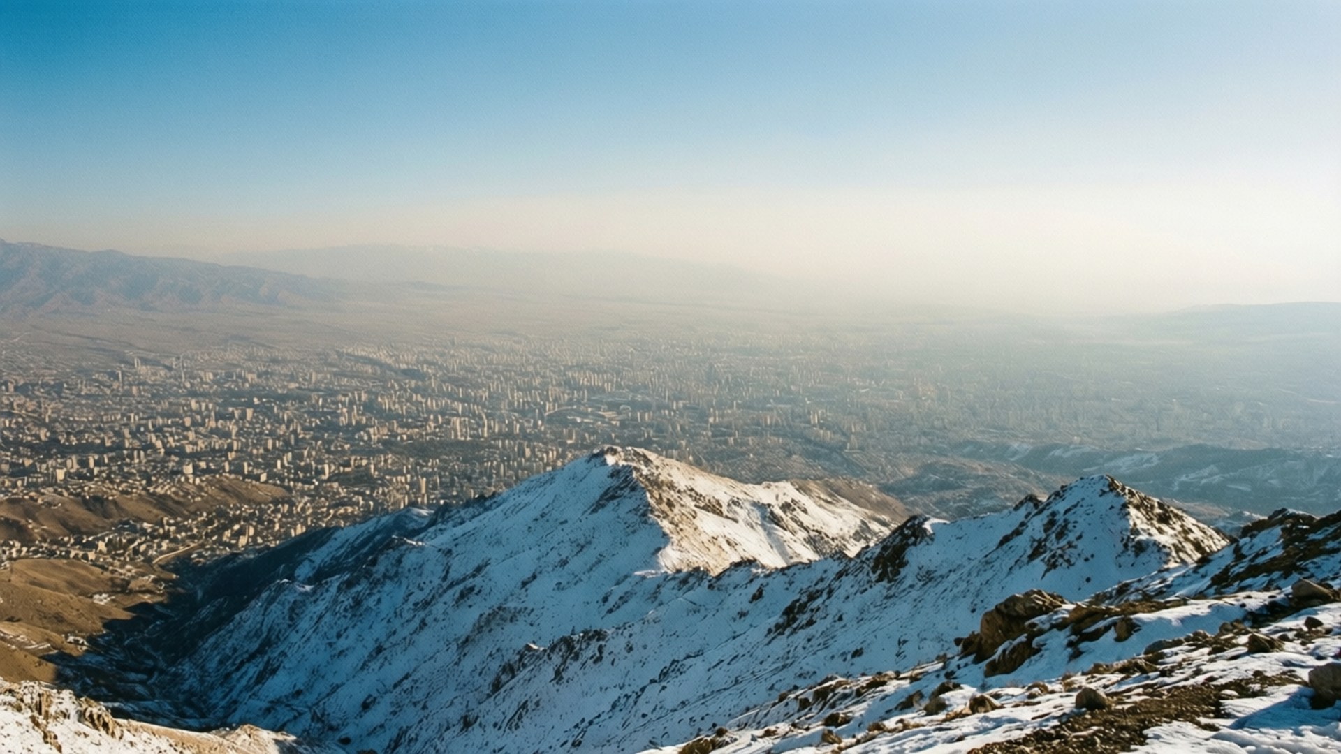 Vista panoramica di Teheran dal Monte Tochal con neve e foschia mattutina.