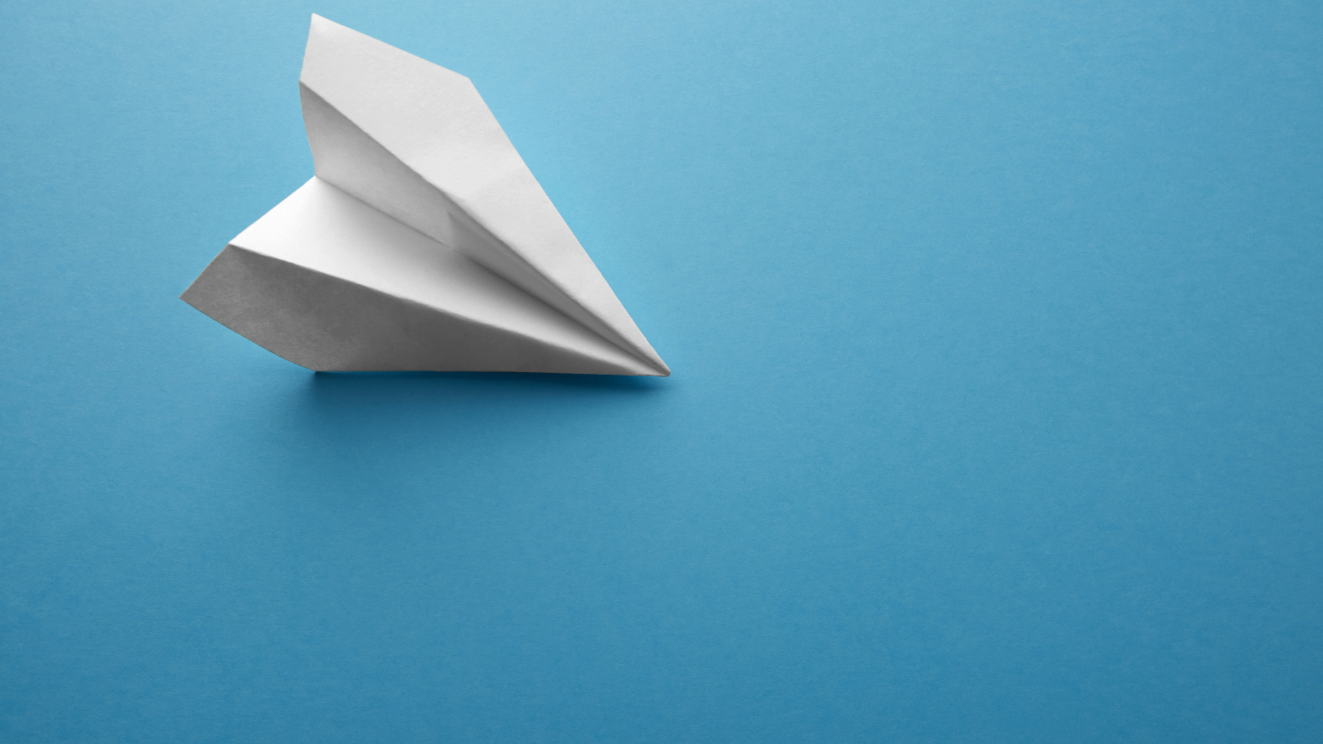 A White Paper Airplane On A Blue Background