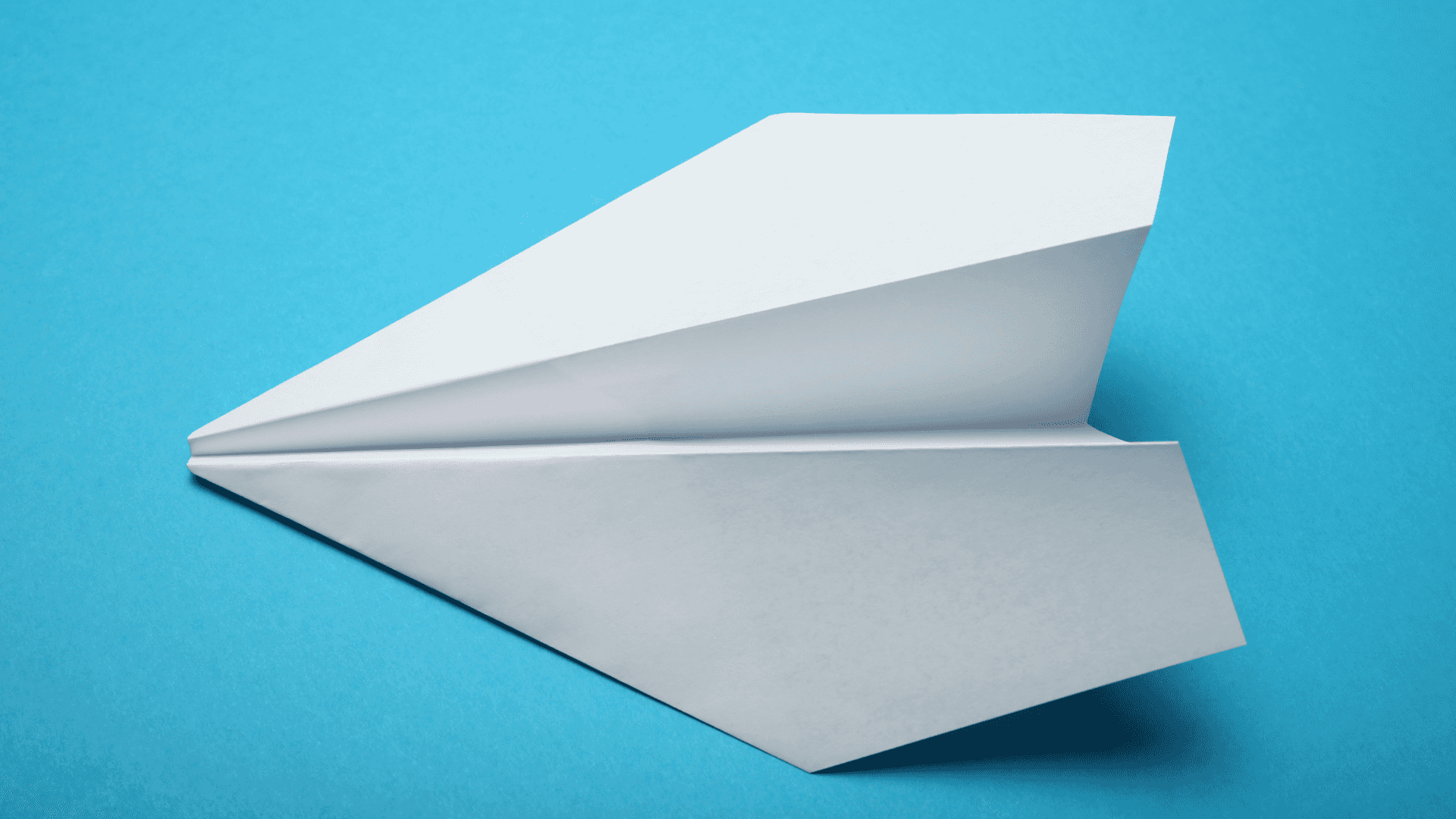 Ettvitt Pappersflygplan På En Blå Bakgrund