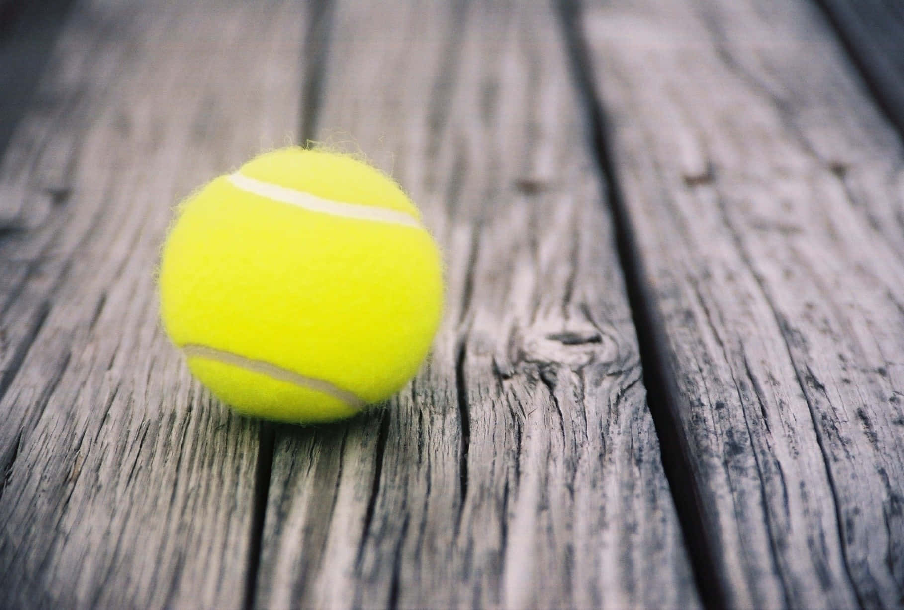 En tennisbold på en træoverflade Wallpaper