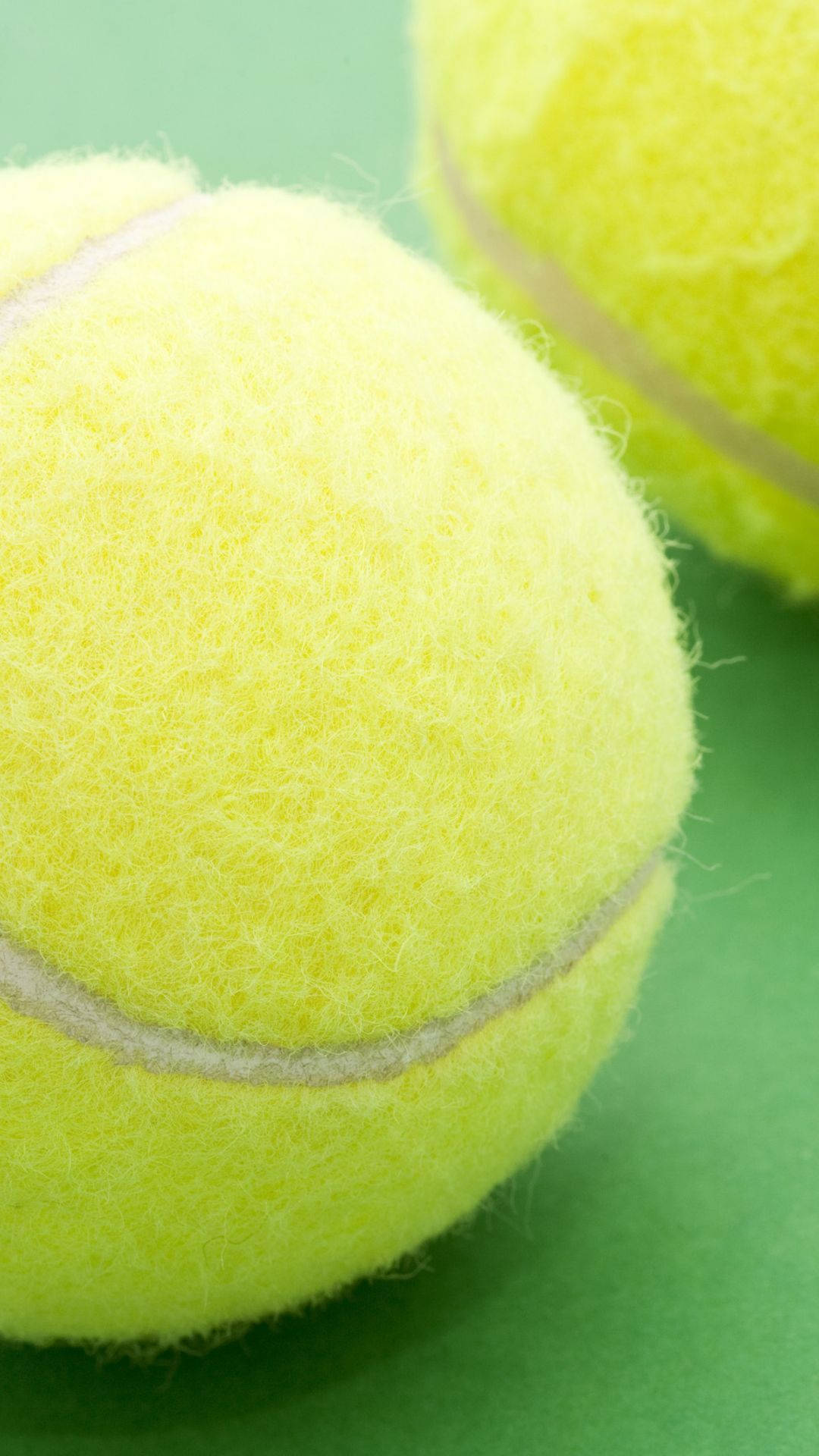 Two Tennis Balls On A Green Surface Wallpaper