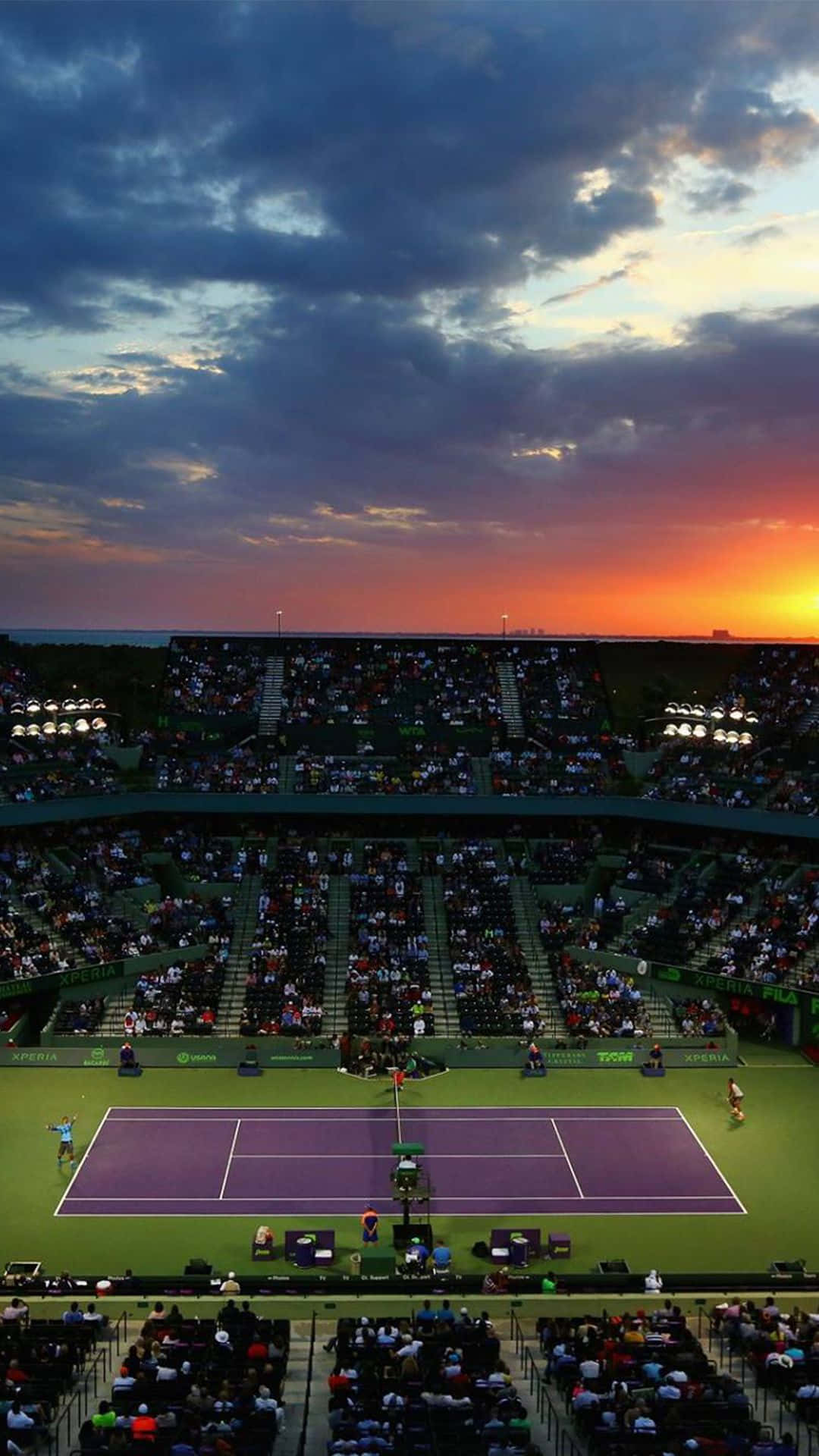A Tennis Court With A Sunset Behind It