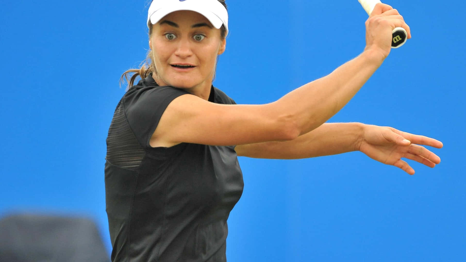 Tennis spiller Monica Niculescu ser tilfreds ud mod en bølgende pal blå baggrund. Wallpaper