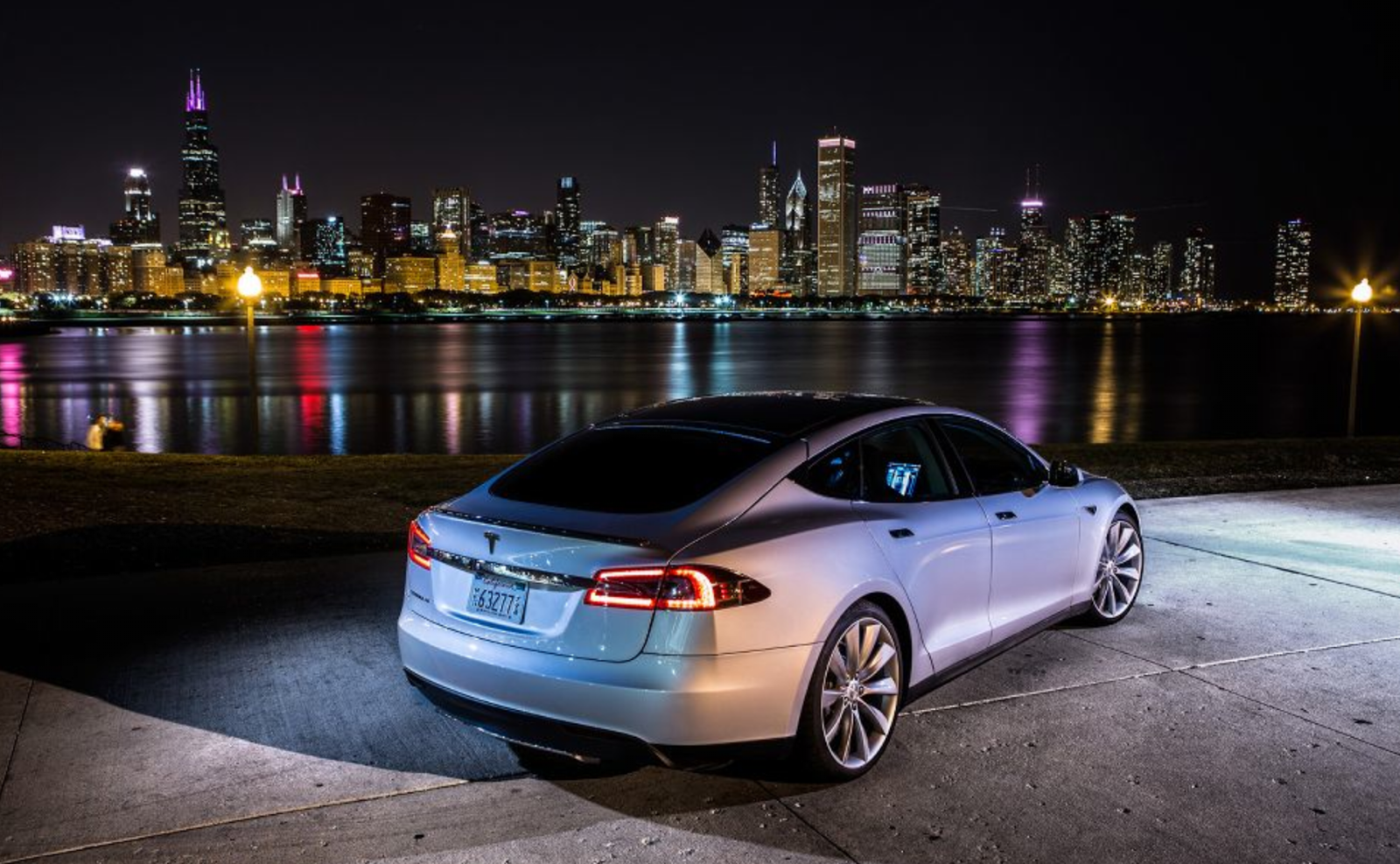 A Tesla Model S electric car driving through a beautiful landscape.