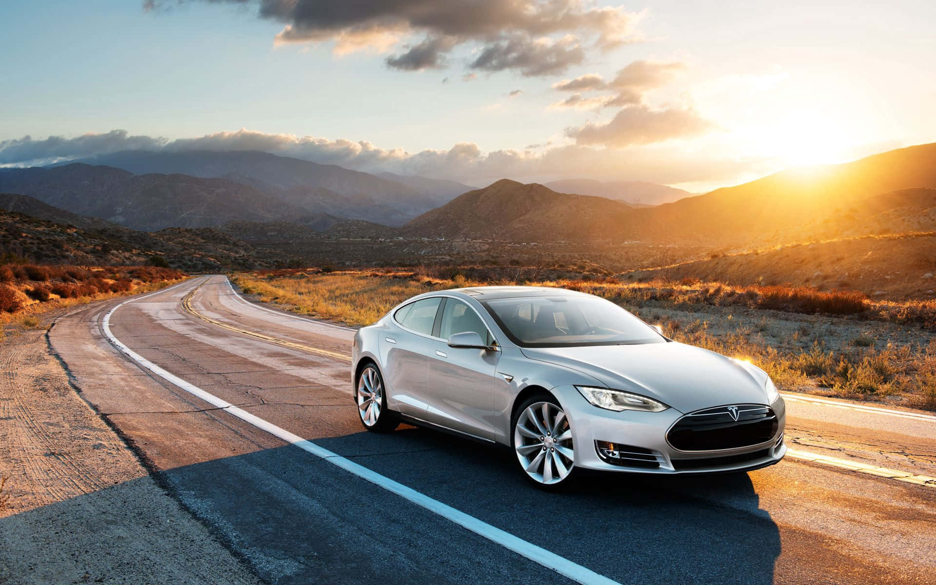 Teslamodel S Kører Ned Ad En Vej I Ørkenen.