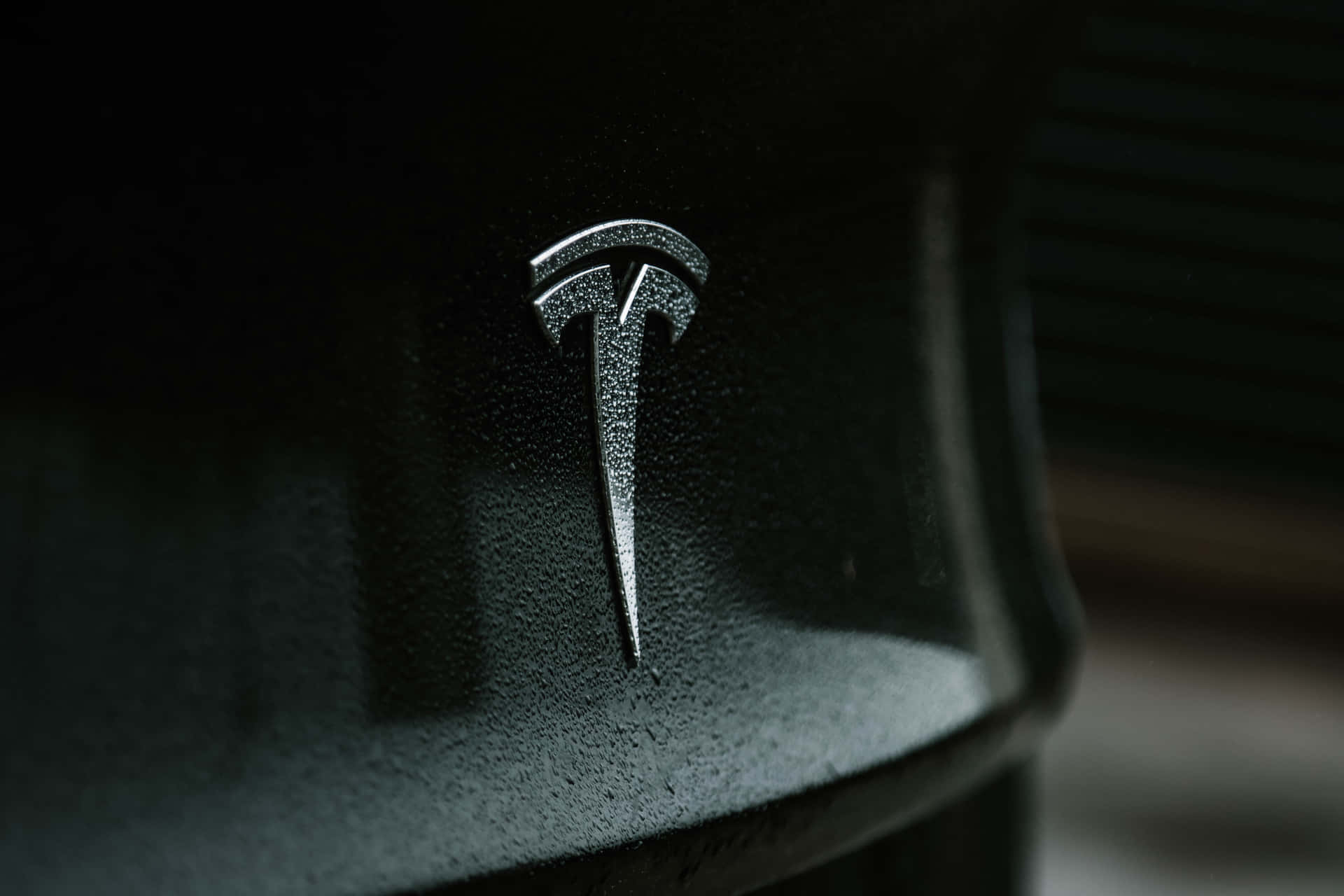 Tesla-logo på siden af ​​en sort bil Wallpaper