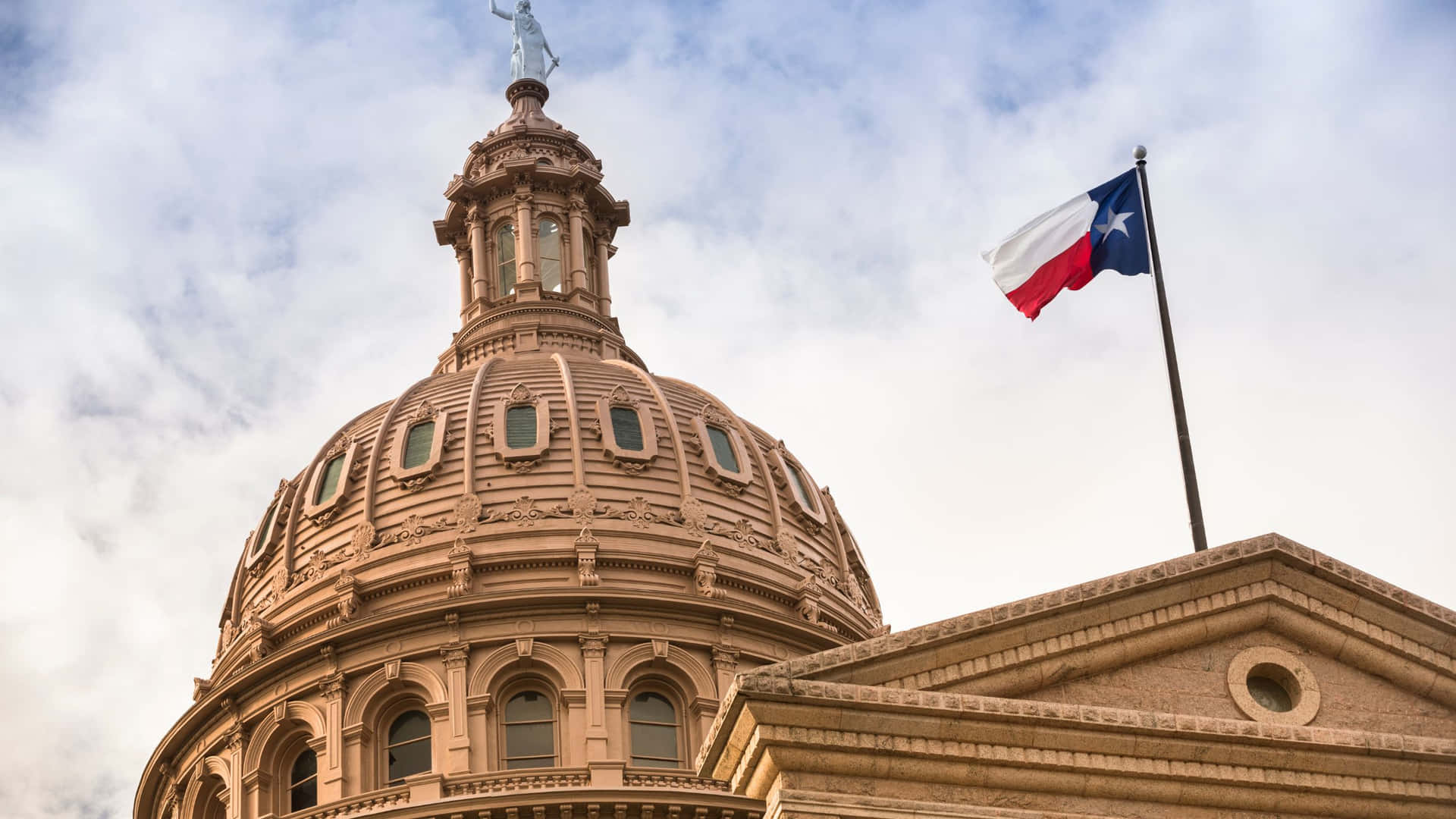Edificiodel Capitolio Del Estado De Texas Con Una Bandera De Texas Ondeando.