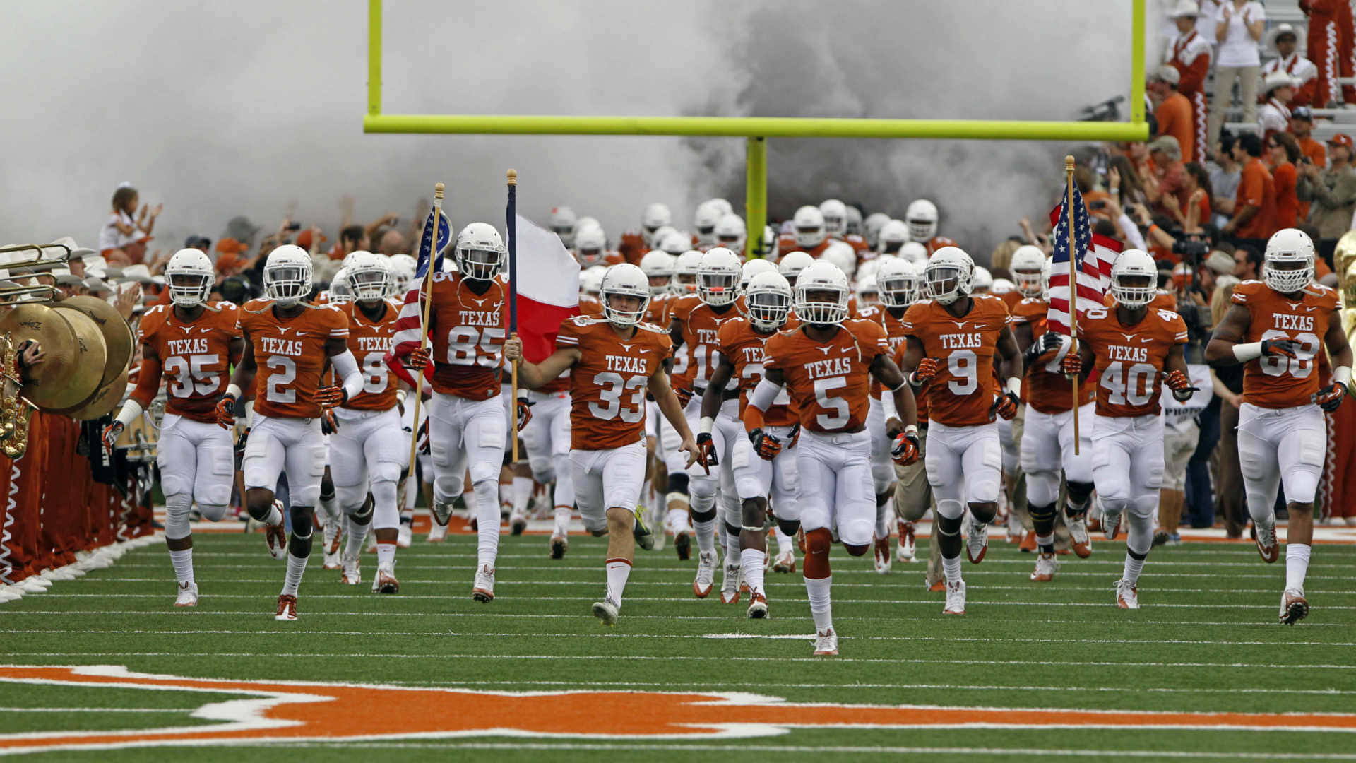 Elequipo De Fútbol Americano De Texas Longhorns Corriendo Hacia El Campo. Fondo de pantalla
