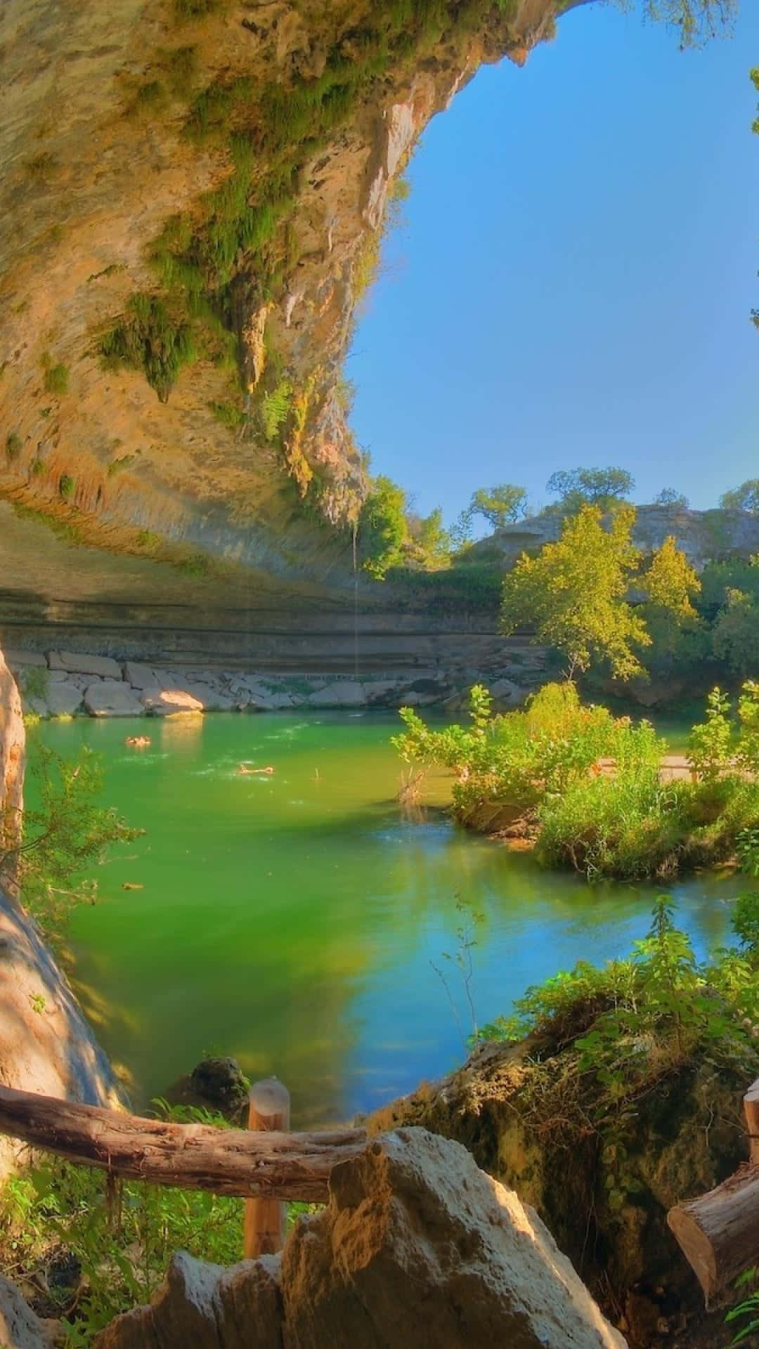 A Cave With A Green River And Trees Wallpaper