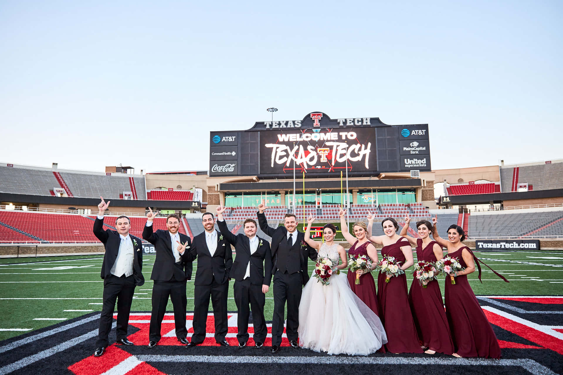 A Wedding Party Poses For A Photo On A Football Field Wallpaper