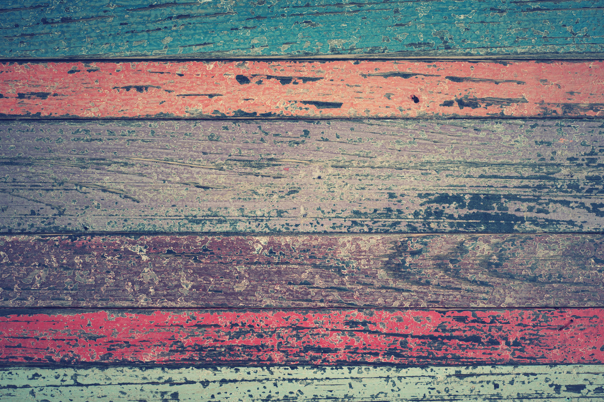 Textured Multi-Colored Wood Fence Wallpaper — Weathered wooden planks with peeling teal red and faded gray paint create a rustic textured background.