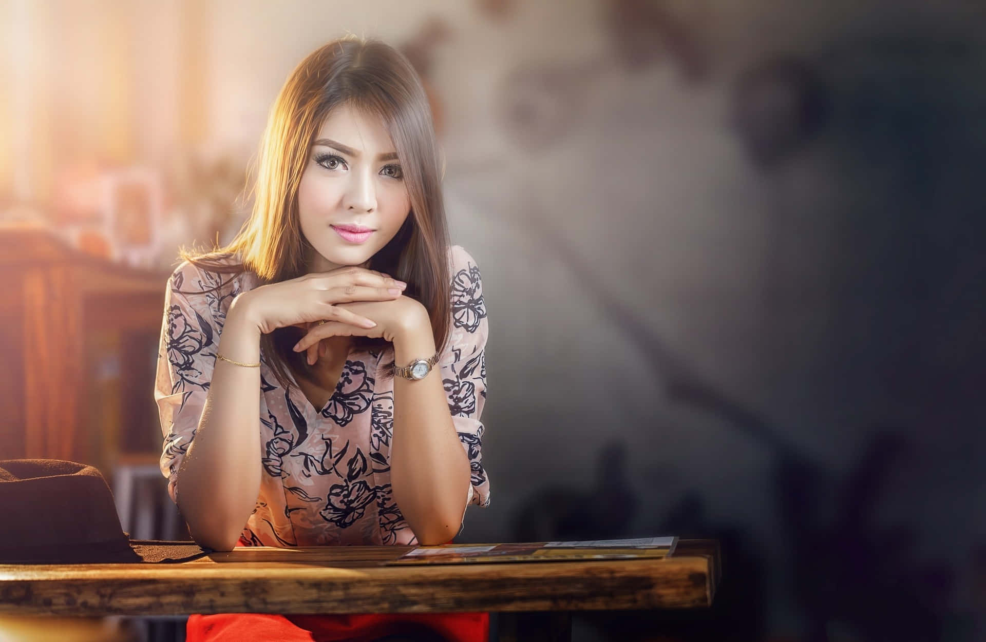 Caption: A Thai Girl Leaning on a Wooden Desk in Traditional Attire Wallpaper