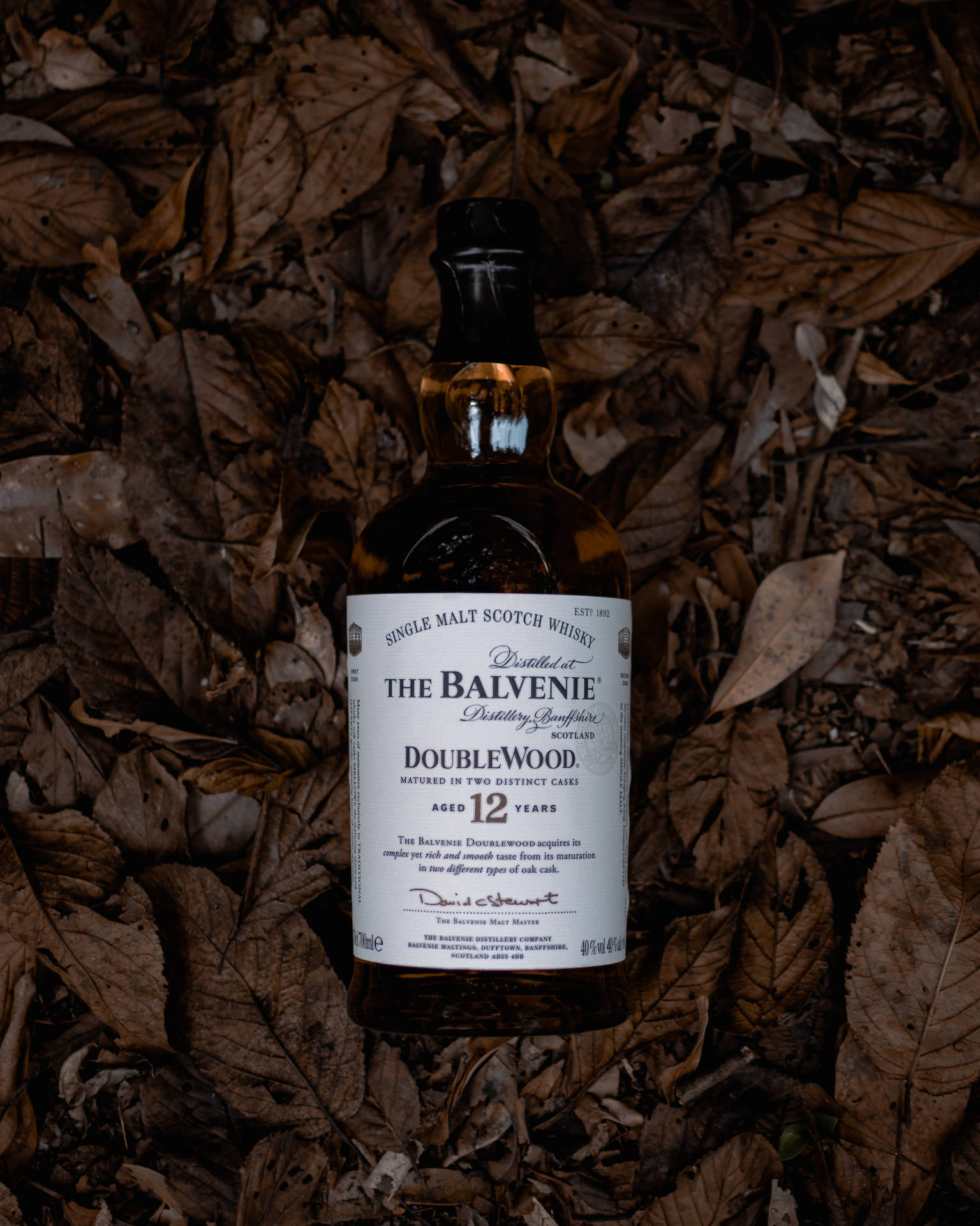 Den Balvenie Whiskey Bottle On Dead Leaves Wallpaper. Wallpaper