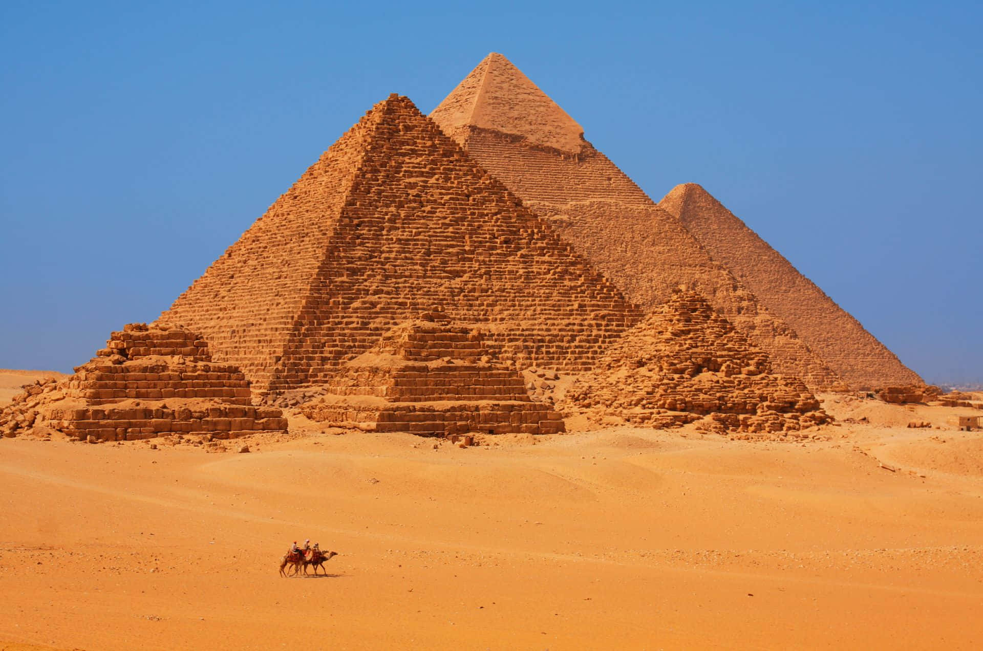Majestic view of the Pyramids of Giza bathed in a rust-colored hue. Wallpaper