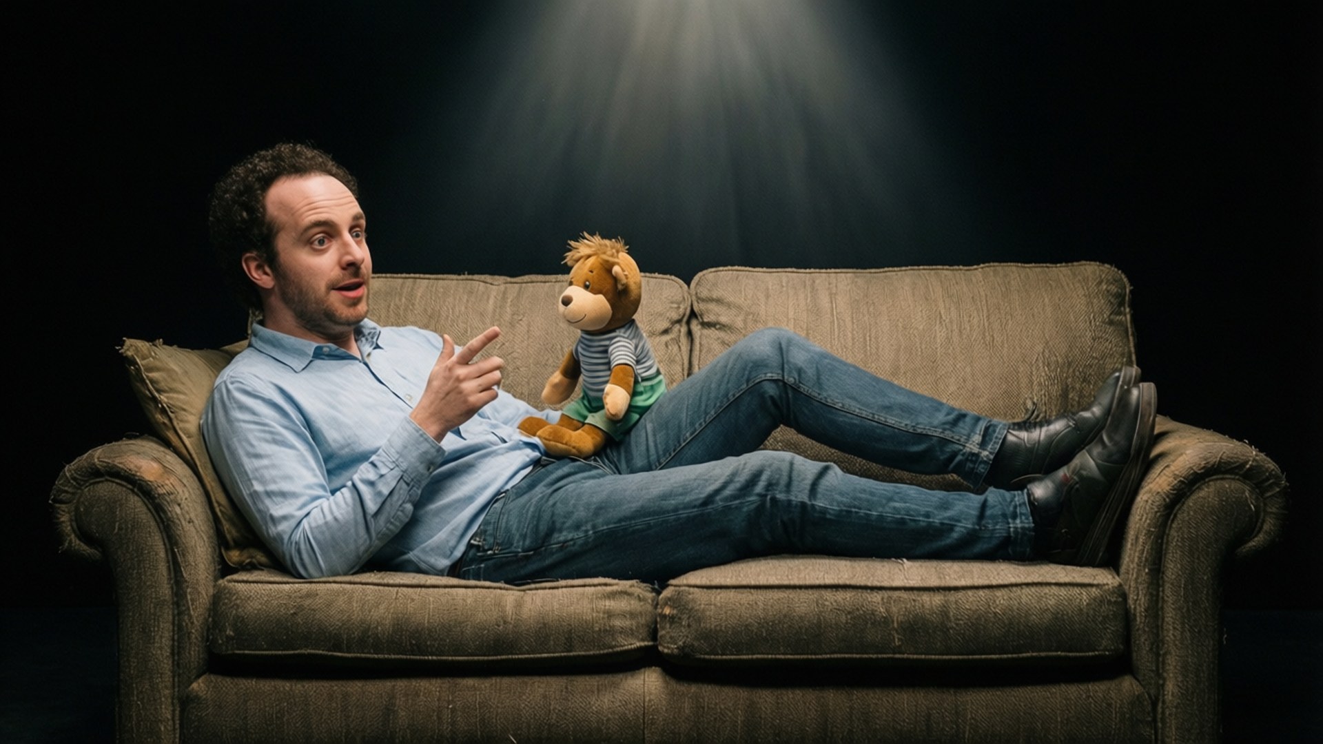Eric Andre on a psychiatrist's couch talking to a stuffed animal, parody therapy.