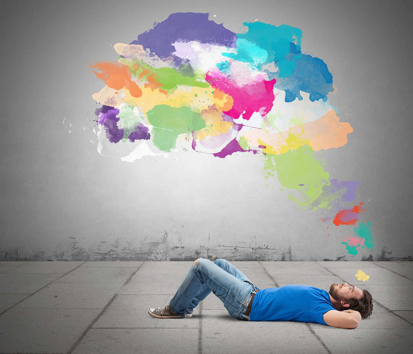 A Man Laying On The Ground With A Colorful Thought Cloud